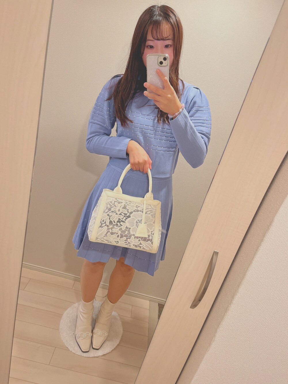 ホワイト系のショルダーバッグ、ホワイト系のブーツ、グレー系のポンチョを着用したレディースの秋コーディネートの2枚目の写真