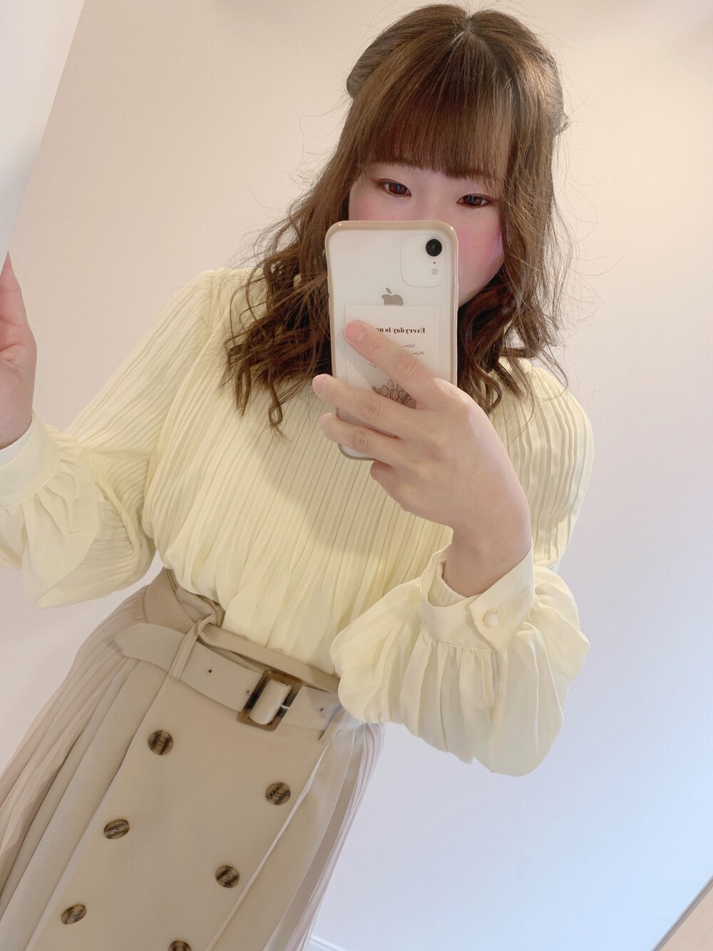 イエロー系のシャツ/ブラウス、ベージュ系のスカート、ホワイト系のパンプスを着用したレディースの春コーディネートの2枚目の写真