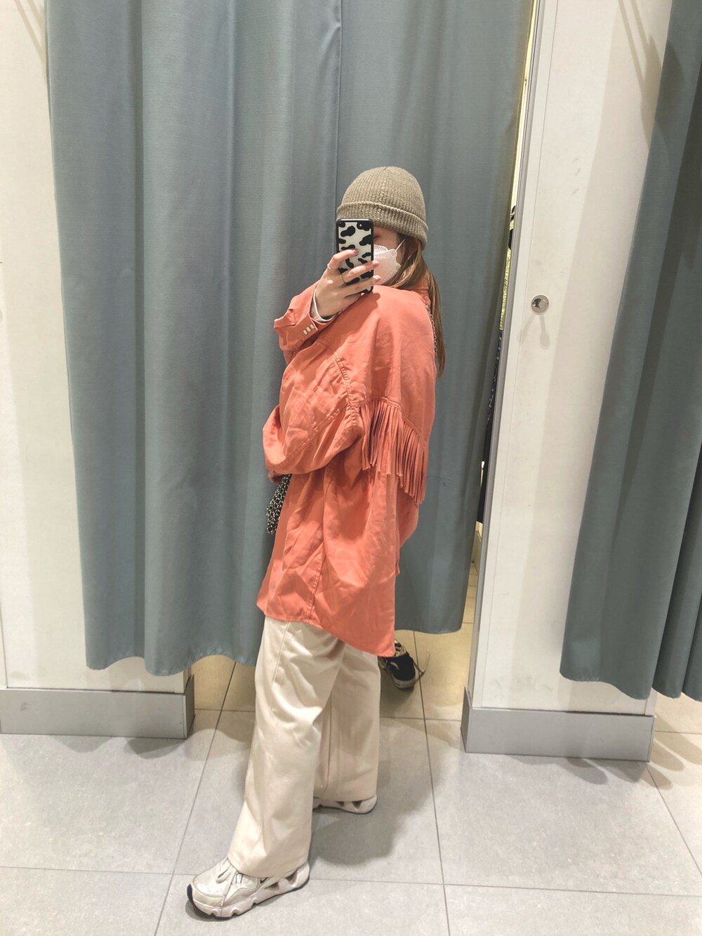 オレンジ系のシャツ/ブラウス、ホワイト系のスニーカー、ブラック系のショルダーバッグを着用したレディースの春コーディネートの3枚目の写真