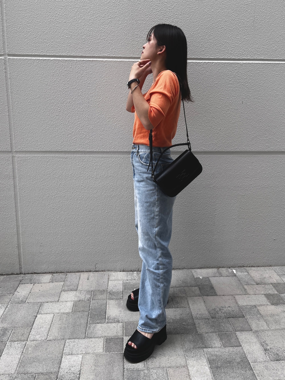ブルー系のデニムパンツ、ブラック系のサンダル、ブラック系のショルダーバッグを着用したレディースの春コーディネートの2枚目の写真