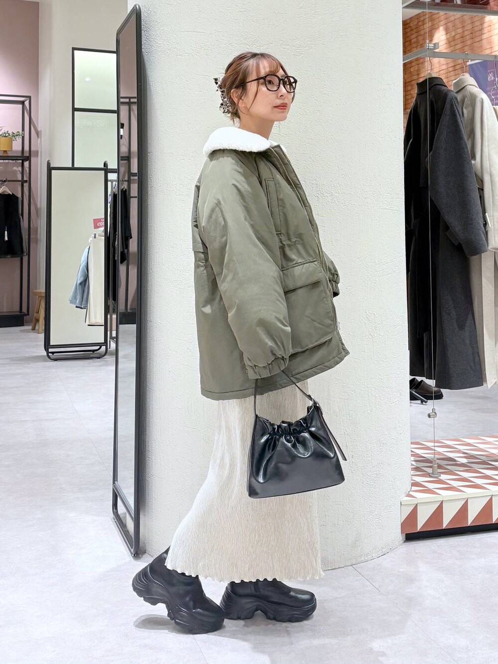 ブラック系のブーツ、グリーン系のその他アウター、ホワイト系のスカートを着用したレディースの冬コーディネートの4枚目の写真