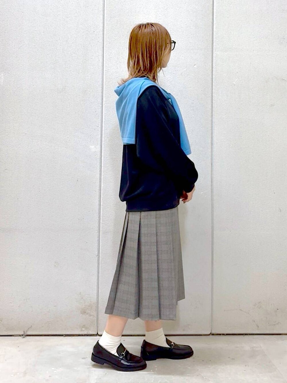 グレー系のスカート、ブラック系のスウェット、ブラック系のローファーを着用したレディースの秋コーディネートの5枚目の写真