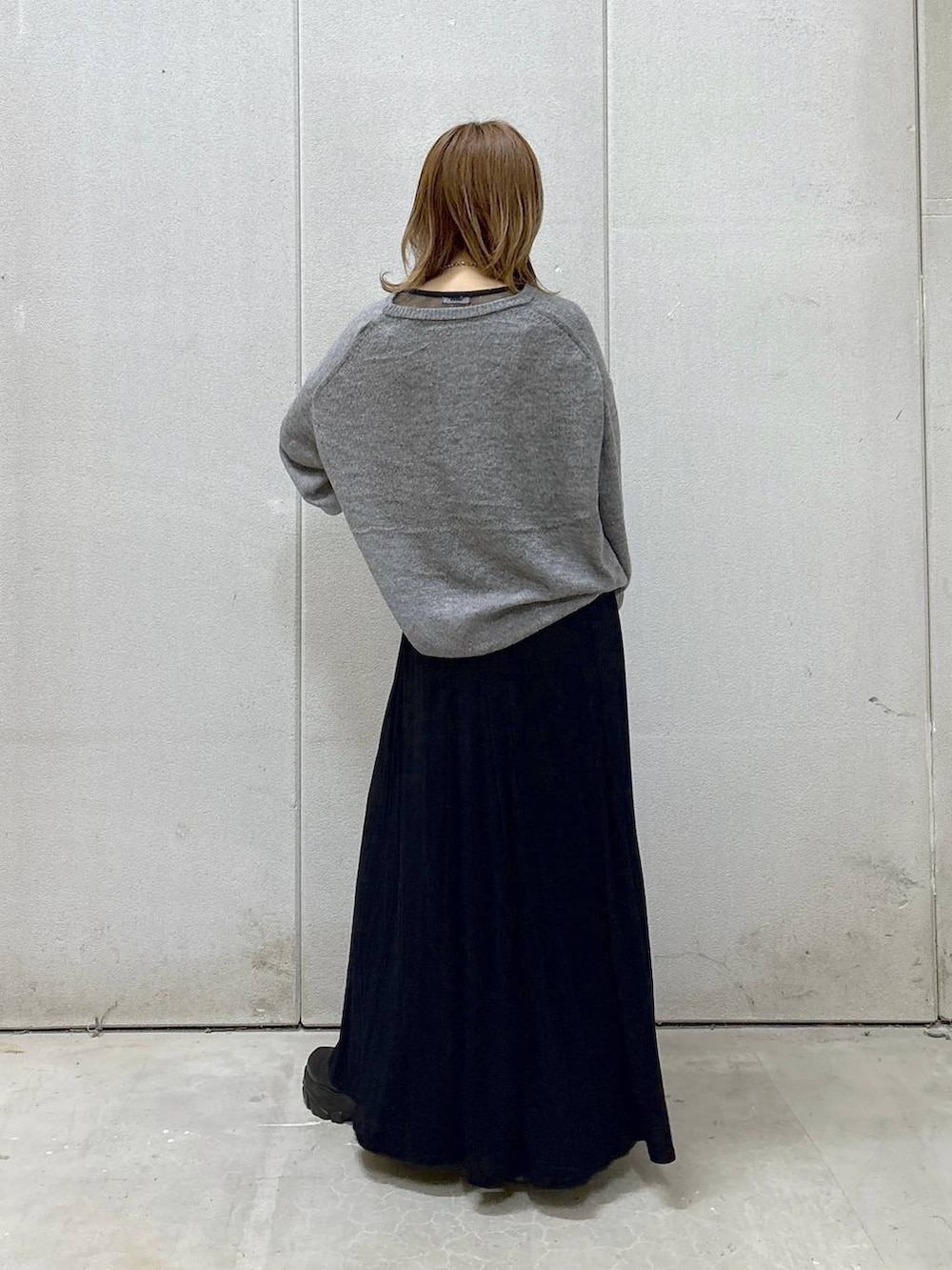 ブラック系のブーツ、ブラック系のスカート、グレー系のニット/セーターを着用したレディースの秋コーディネートの2枚目の写真