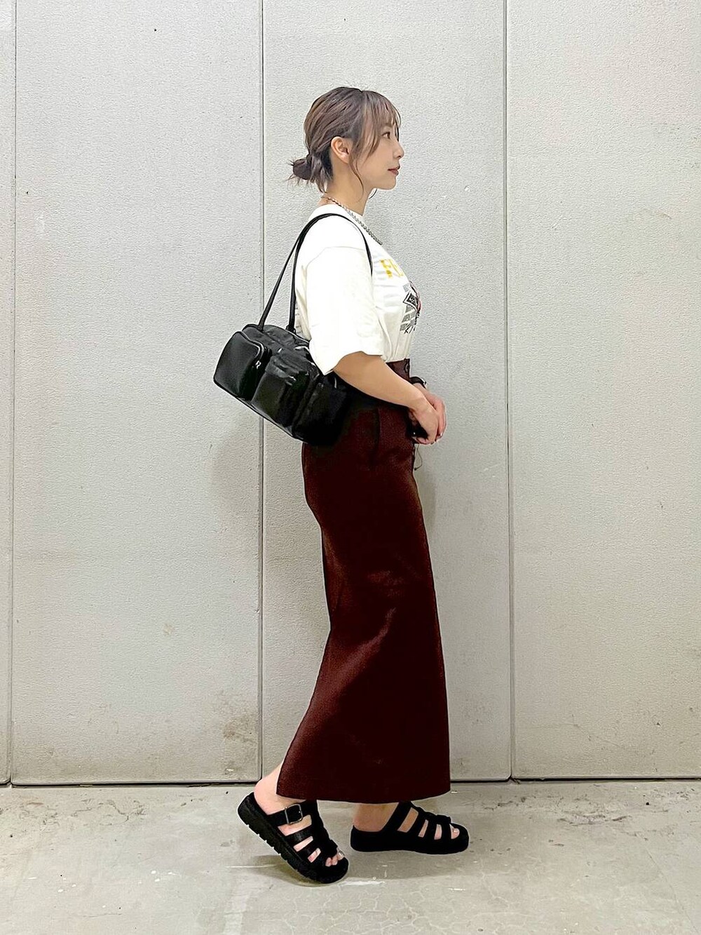 ブラウン系のスカート、ホワイト系のTシャツ/カットソー、ブラック系のスニーカーを着用したレディースの夏コーディネートの3枚目の写真