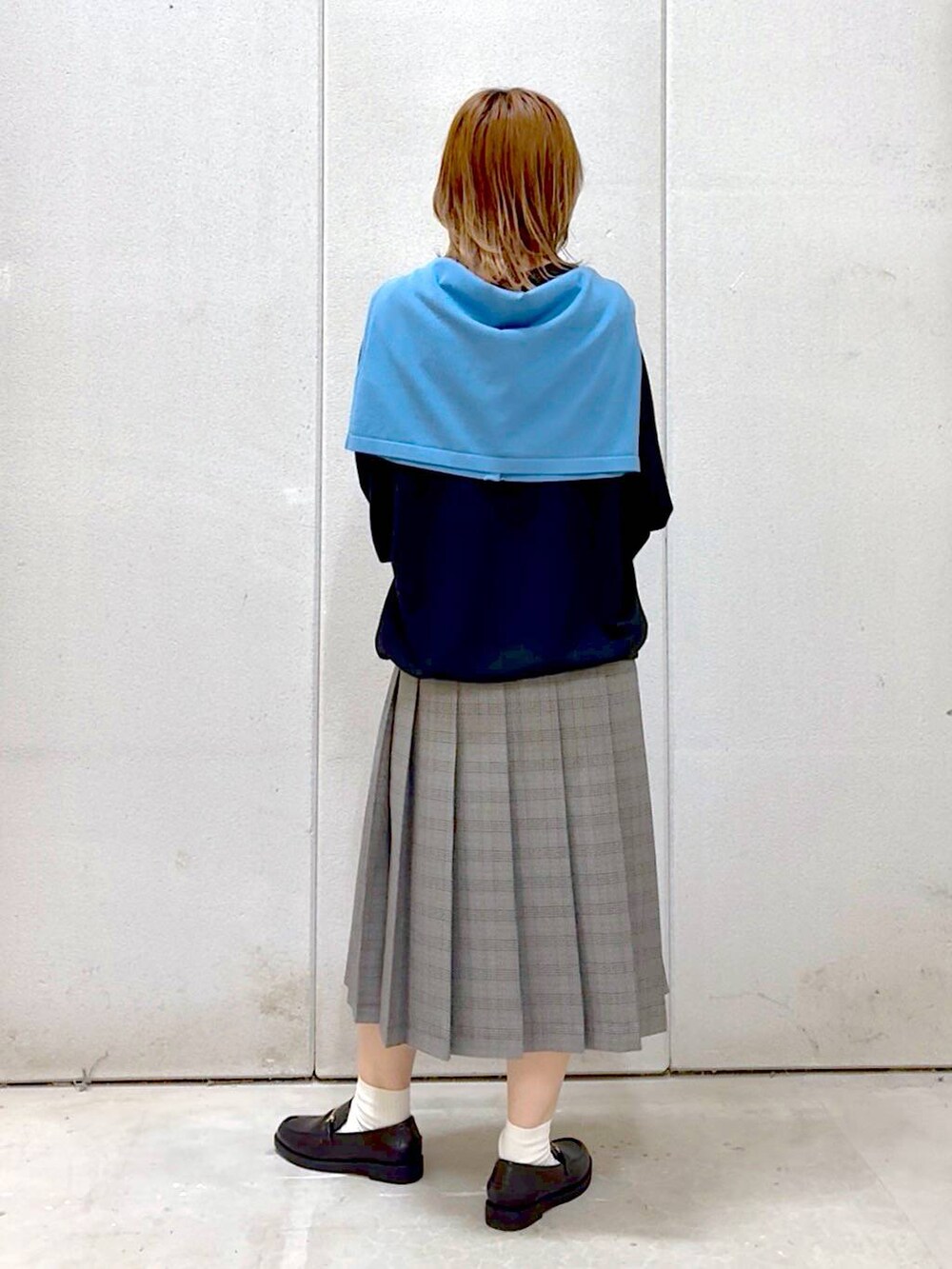 グレー系のスカート、ブラック系のスウェット、ブラック系のローファーを着用したレディースの秋コーディネートの4枚目の写真