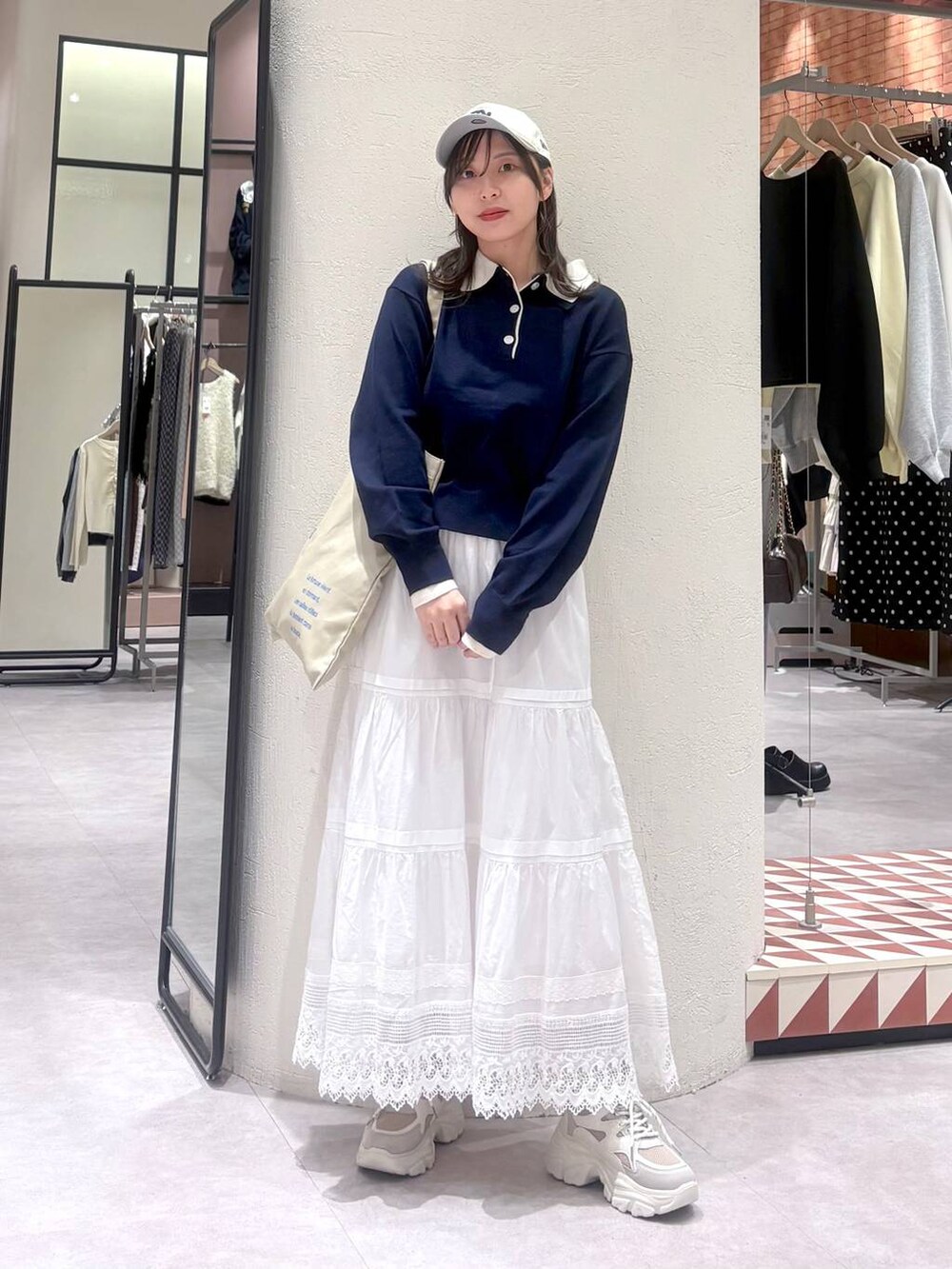 ベージュ系のトートバッグ、ホワイト系のスカート、ベージュ系のスニーカーを着用したレディースの冬コーディネートの4枚目の写真