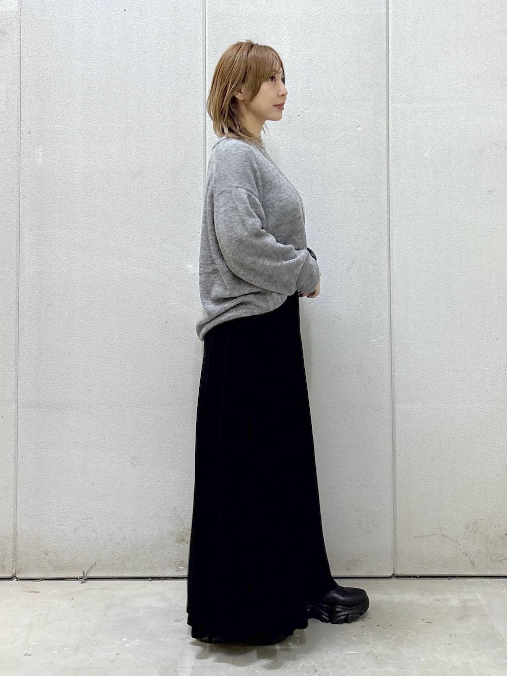 ブラック系のブーツ、ブラック系のスカート、グレー系のニット/セーターを着用したレディースの秋コーディネートの3枚目の写真