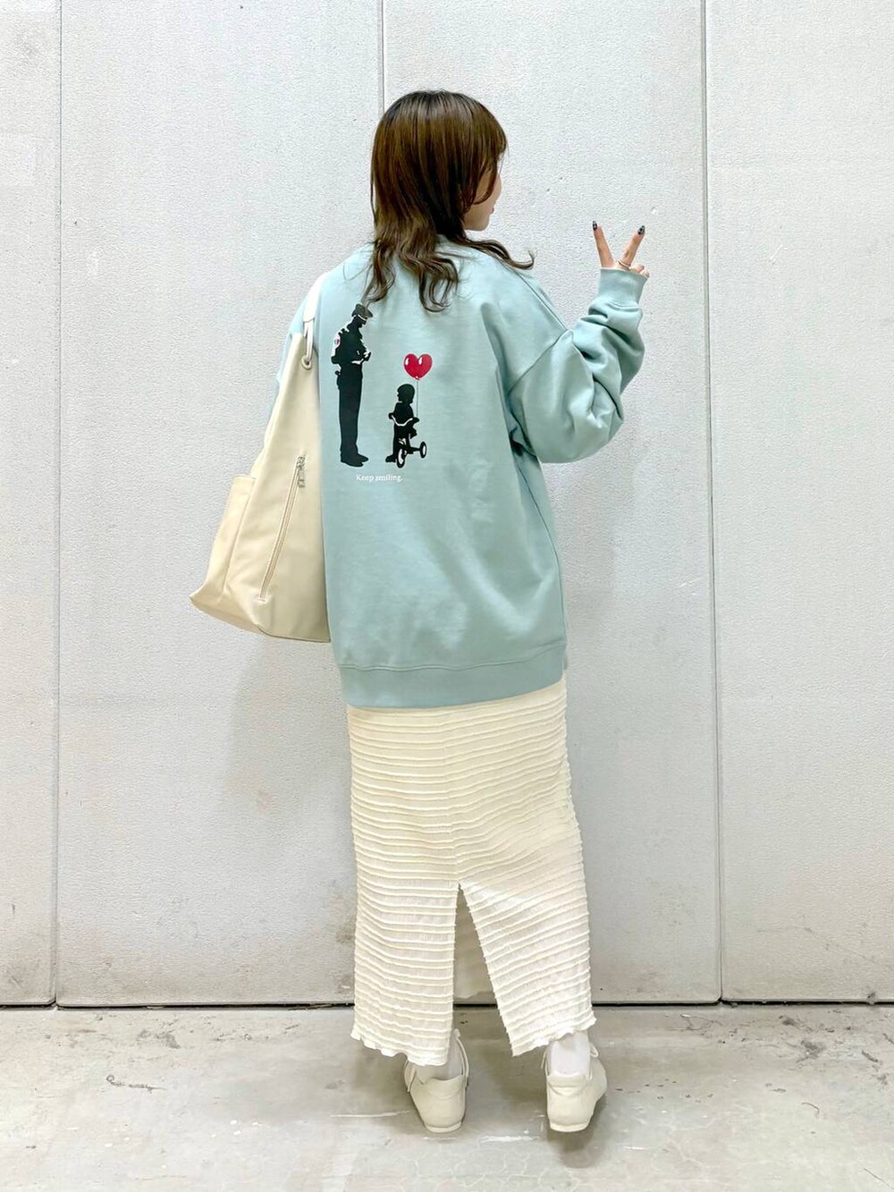 グリーン系のTシャツ/カットソー、ホワイト系のトートバッグ、ホワイト系のスニーカーを着用したレディースの冬コーディネートの4枚目の写真