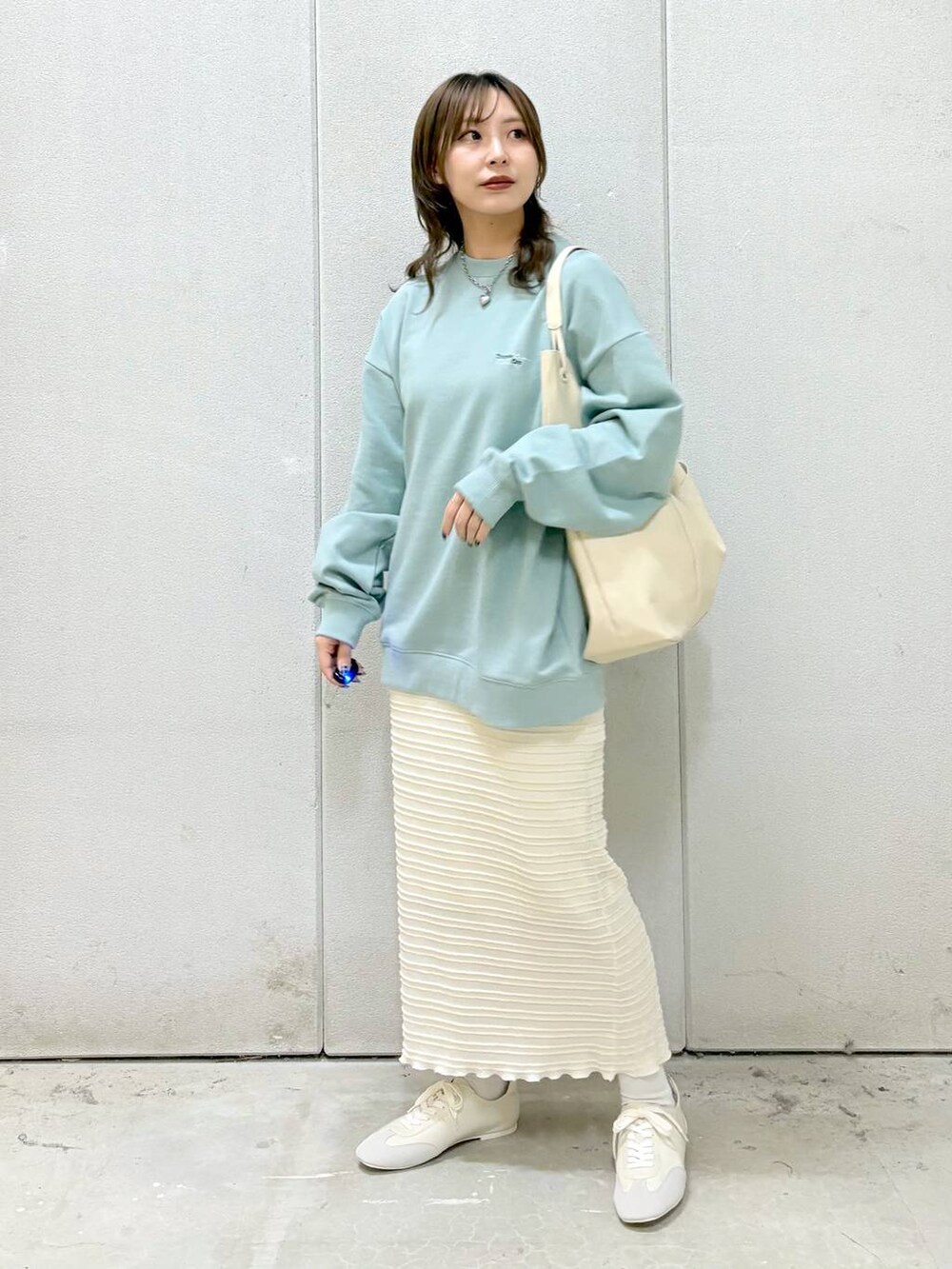 グリーン系のTシャツ/カットソー、ホワイト系のトートバッグ、ホワイト系のスニーカーを着用したレディースの冬コーディネートの6枚目の写真