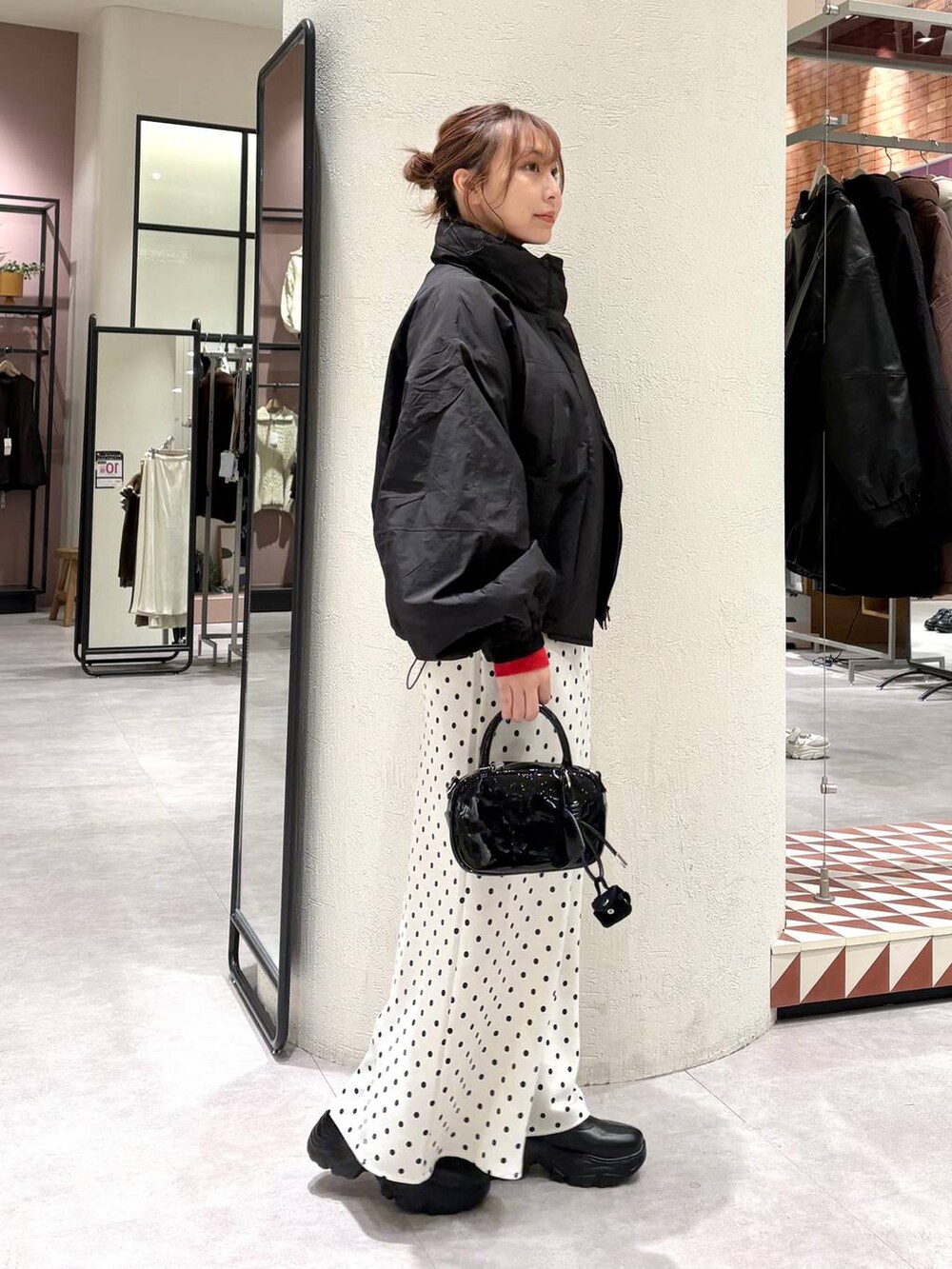 ブラック系のその他アウター、ブラック系のブーツ、ホワイト系のスカートを着用したレディースの秋コーディネートの4枚目の写真