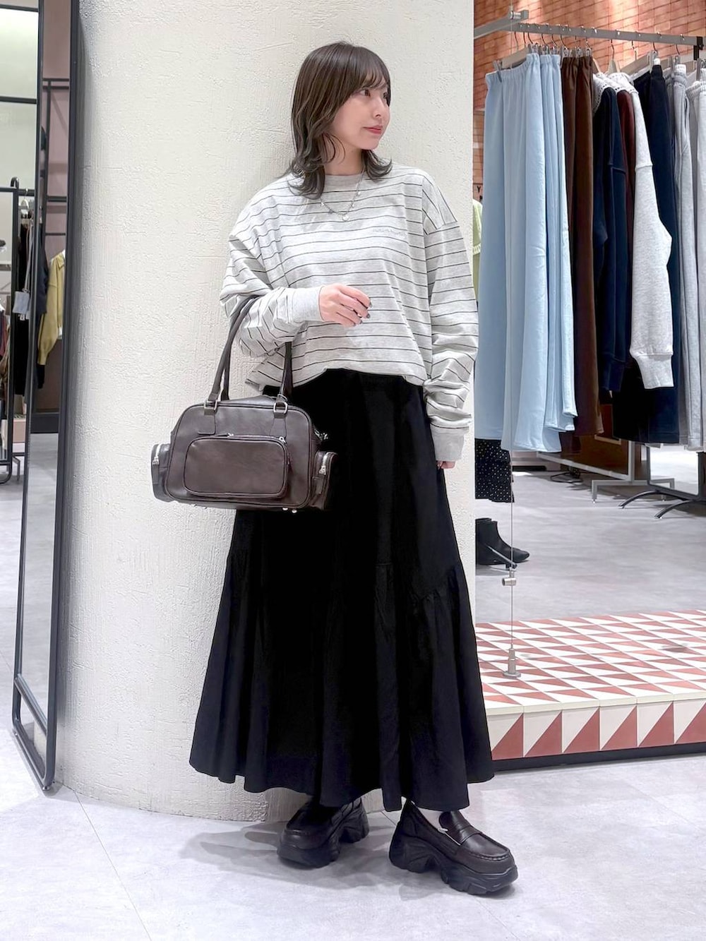 ブラウン系のボストンバッグ、ブラウン系のローファー、グレー系のTシャツ/カットソーを着用したレディースの冬コーディネートの2枚目の写真