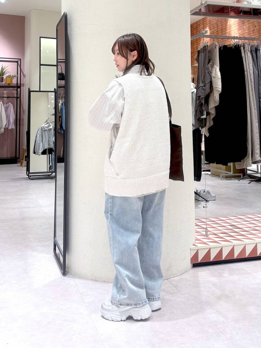 ブルー系のデニムパンツ、ブラウン系のトートバッグ、グレー系のシャツ/ブラウスを着用したレディースの春コーディネートの2枚目の写真