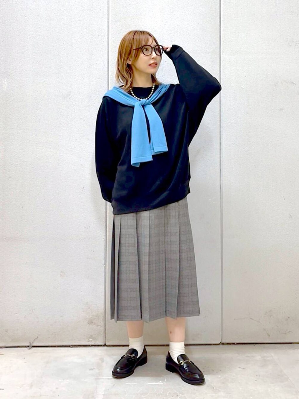 グレー系のスカート、ブラック系のスウェット、ブラック系のローファーを着用したレディースの秋コーディネートの3枚目の写真