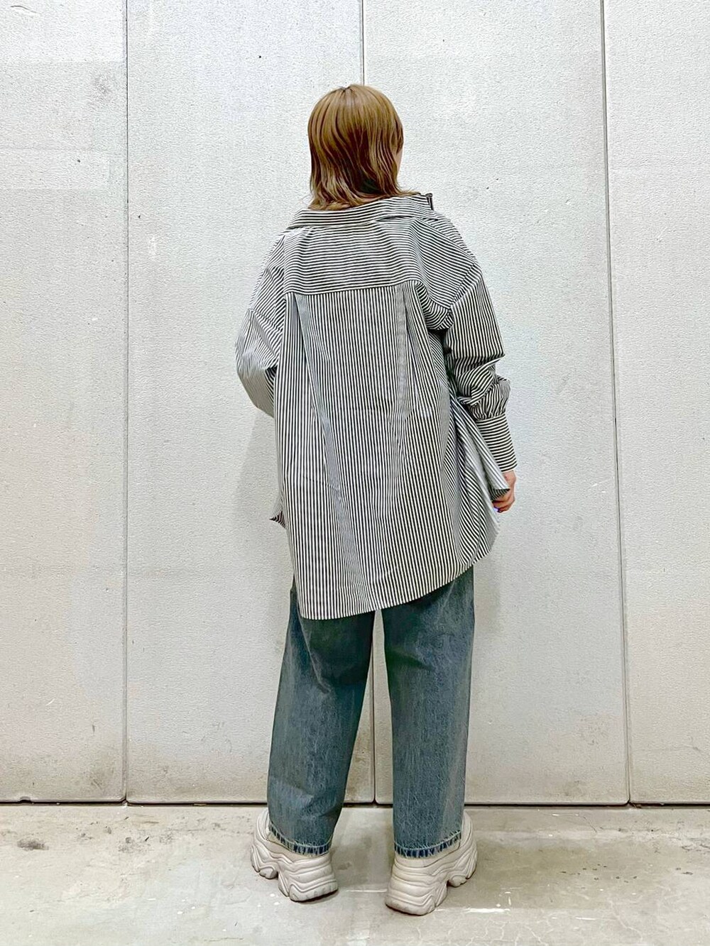 ホワイト系のTシャツ/カットソー、グレー系のスニーカー、ブルー系のデニムパンツを着用したレディースの春コーディネートの3枚目の写真