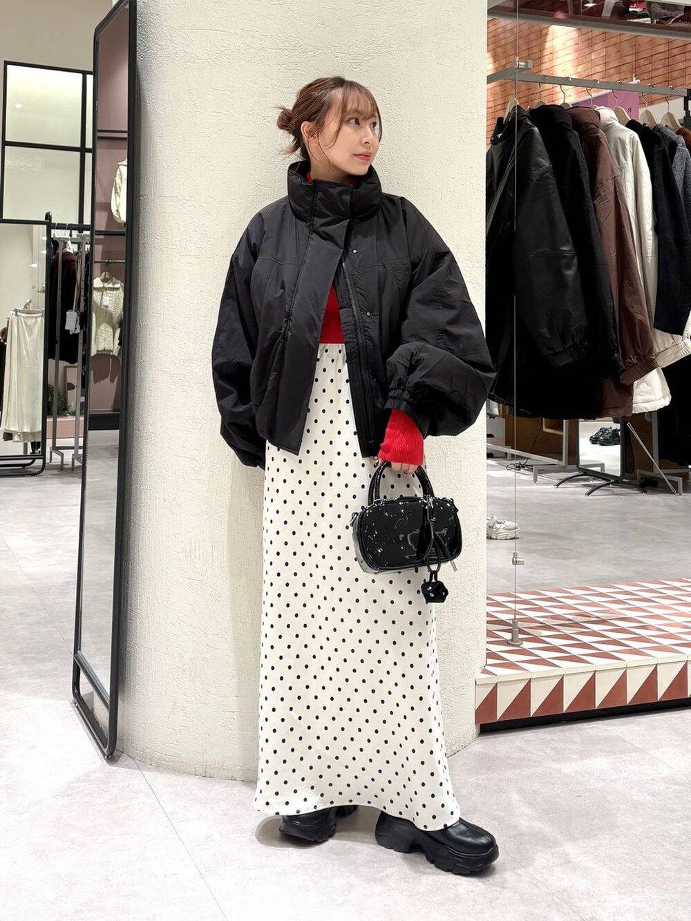 ブラック系のその他アウター、ブラック系のブーツ、ホワイト系のスカートを着用したレディースの秋コーディネートの2枚目の写真