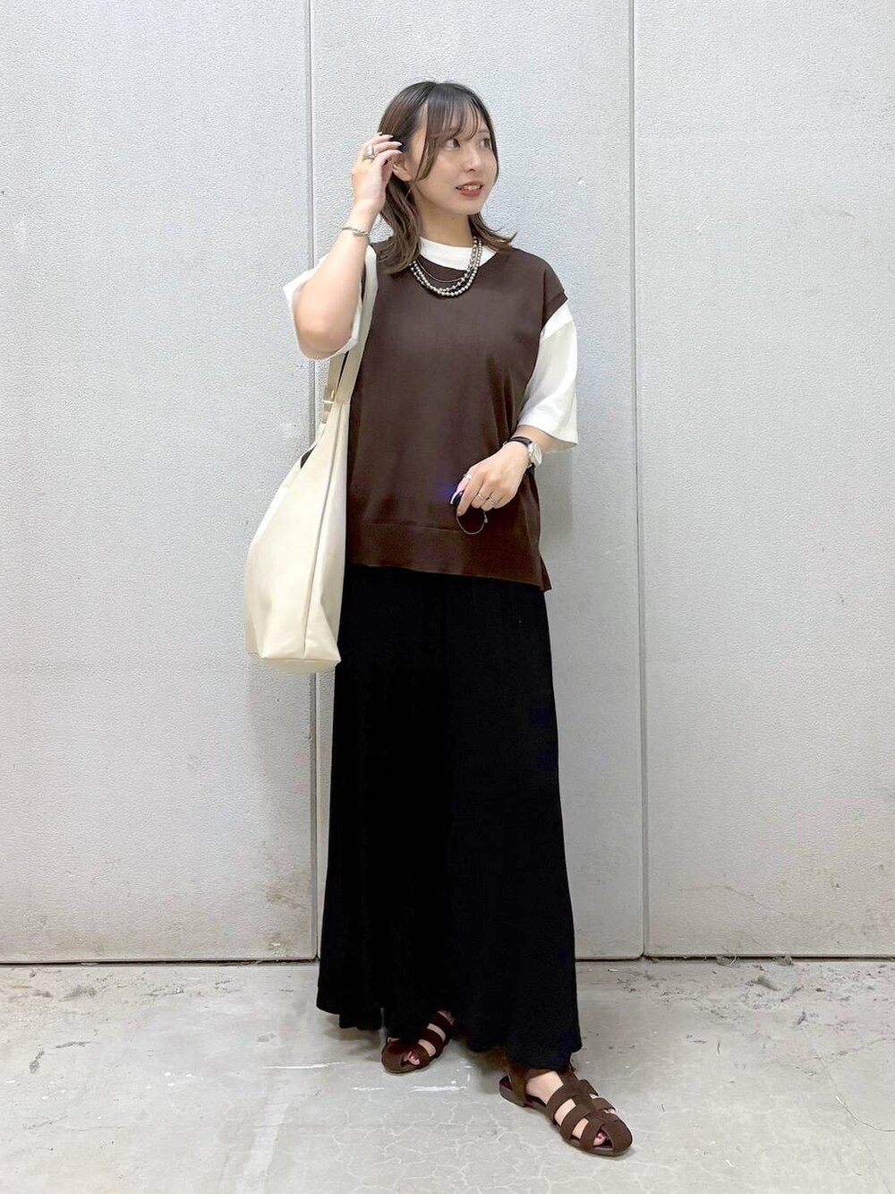 ホワイト系のショルダーバッグ、ホワイト系のTシャツ/カットソー、ブラウン系のサンダルを着用したレディースの夏コーディネートの2枚目の写真