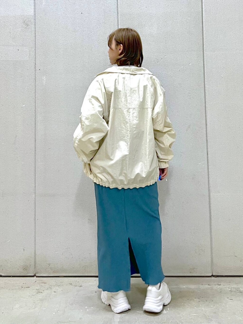 ブルー系のスカート、ホワイト系のスニーカー、グレー系のTシャツ/カットソーを着用したレディースの冬コーディネートの2枚目の写真