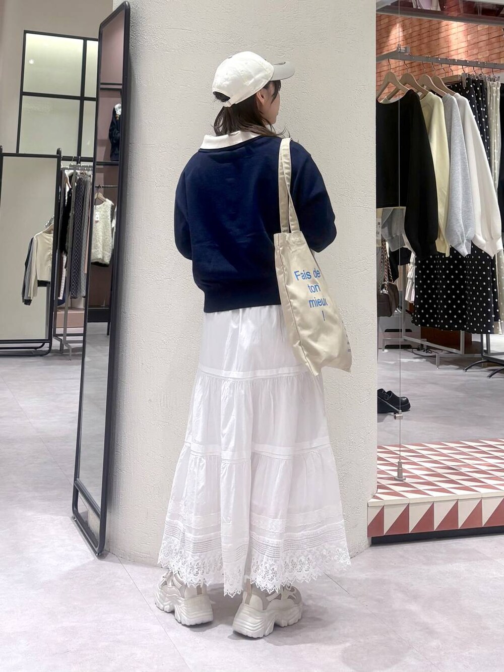 ベージュ系のトートバッグ、ホワイト系のスカート、ベージュ系のスニーカーを着用したレディースの冬コーディネートの2枚目の写真