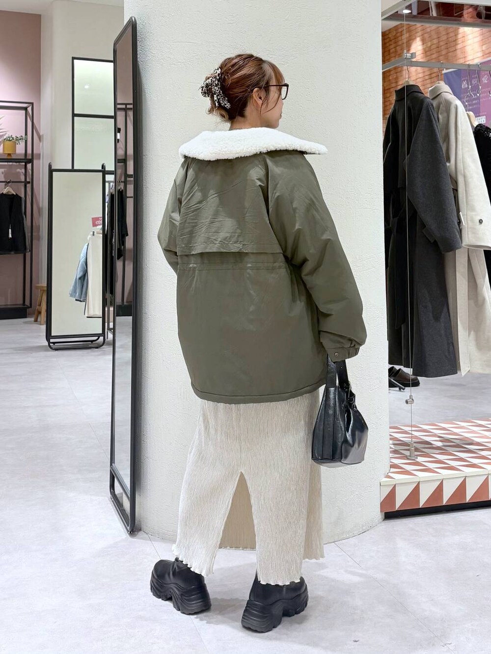 ブラック系のブーツ、グリーン系のその他アウター、ホワイト系のスカートを着用したレディースの冬コーディネートの3枚目の写真