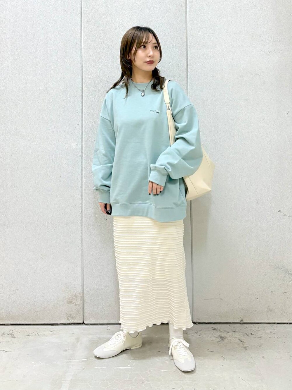 グリーン系のTシャツ/カットソー、ホワイト系のトートバッグ、ホワイト系のスニーカーを着用したレディースの冬コーディネートの3枚目の写真