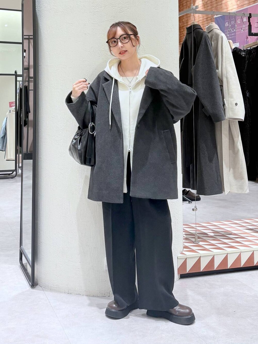 ベージュ系のパーカー、グレー系のその他アウター、ブラック系のスラックスを着用したレディースの冬コーディネートの2枚目の写真