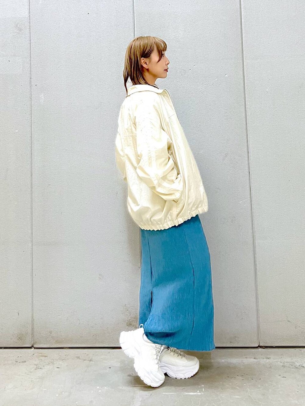 ブルー系のスカート、ホワイト系のスニーカー、グレー系のTシャツ/カットソーを着用したレディースの冬コーディネートの3枚目の写真