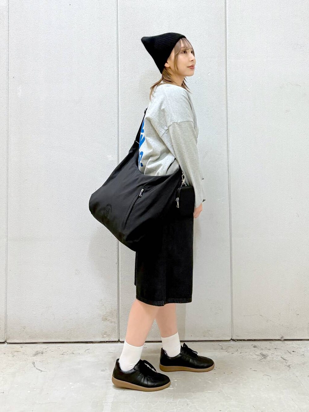 グレー系のワンピース、ブラック系のショルダーバッグ、ブラック系のスニーカーを着用したレディースの春コーディネートの5枚目の写真