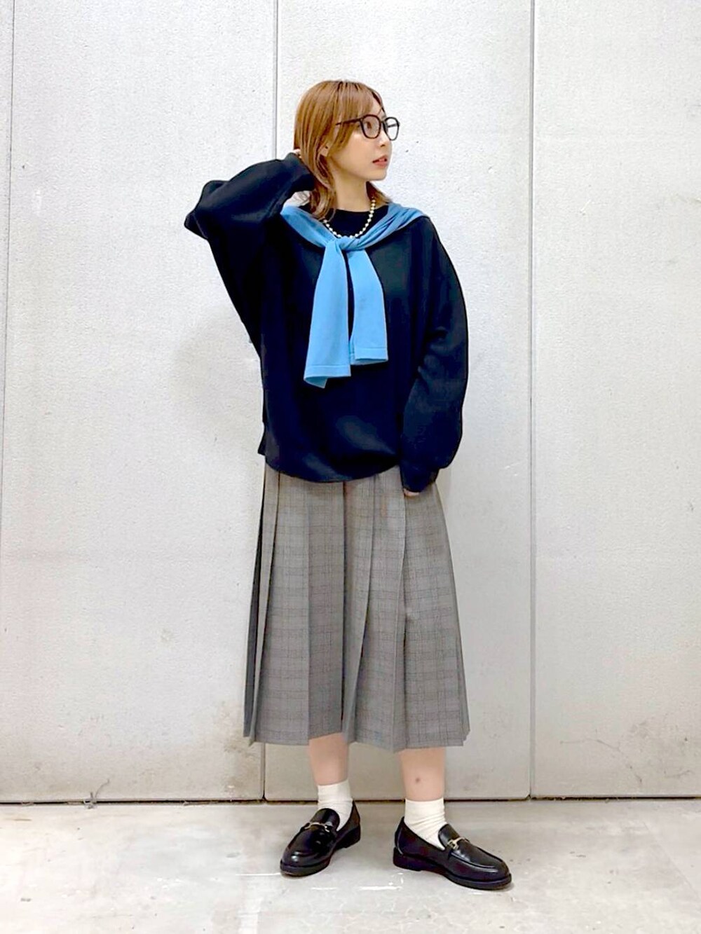 グレー系のスカート、ブラック系のスウェット、ブラック系のローファーを着用したレディースの秋コーディネートの6枚目の写真