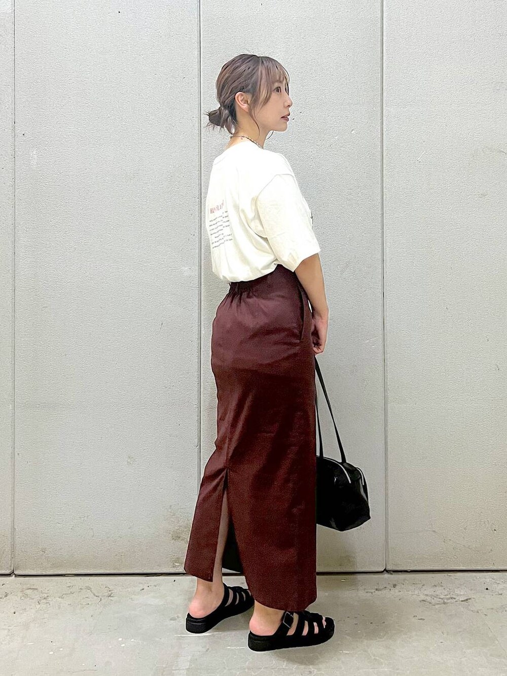 ブラウン系のスカート、ホワイト系のTシャツ/カットソー、ブラック系のスニーカーを着用したレディースの夏コーディネートの2枚目の写真