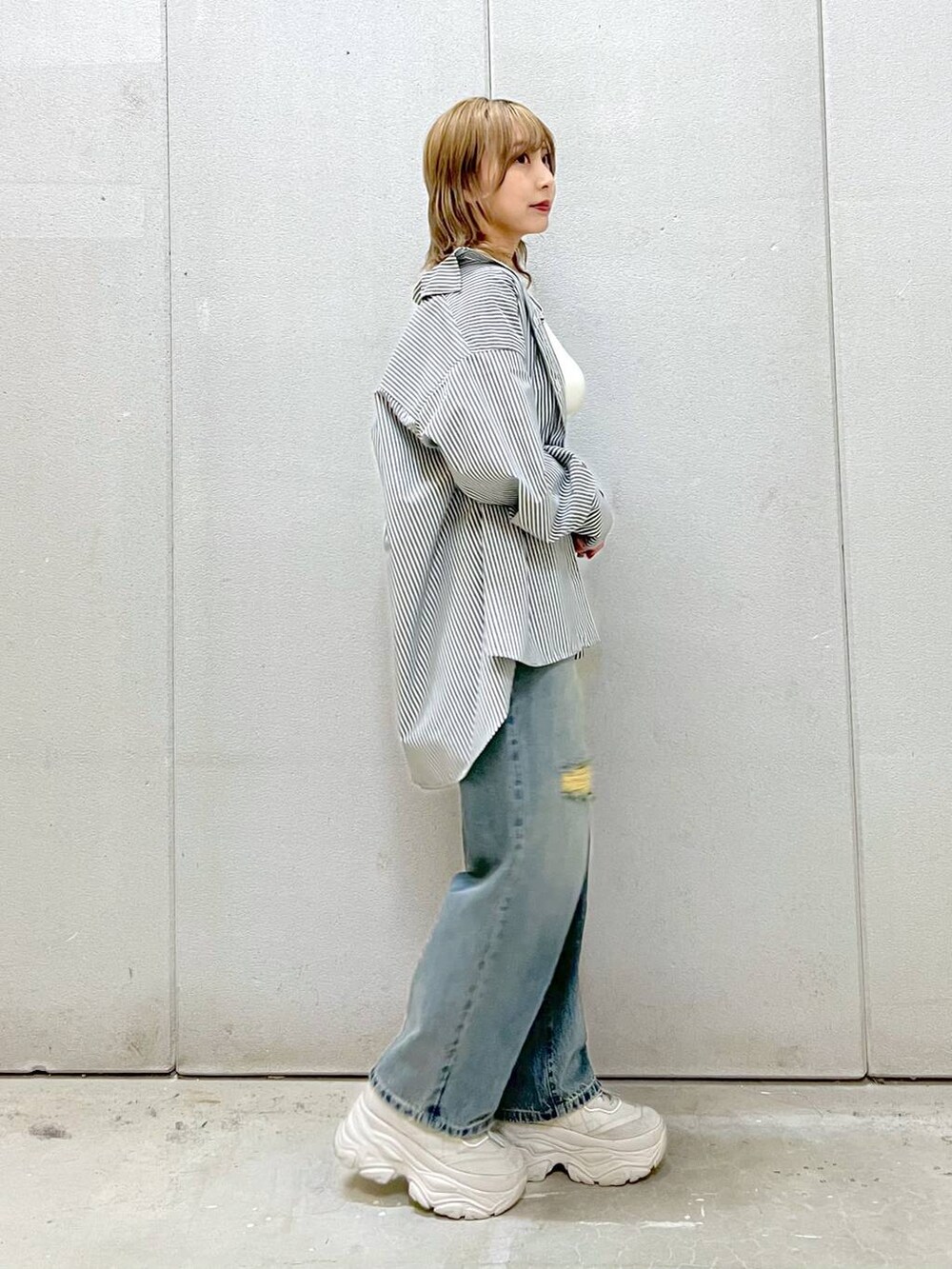 ホワイト系のTシャツ/カットソー、グレー系のスニーカー、ブルー系のデニムパンツを着用したレディースの春コーディネートの4枚目の写真