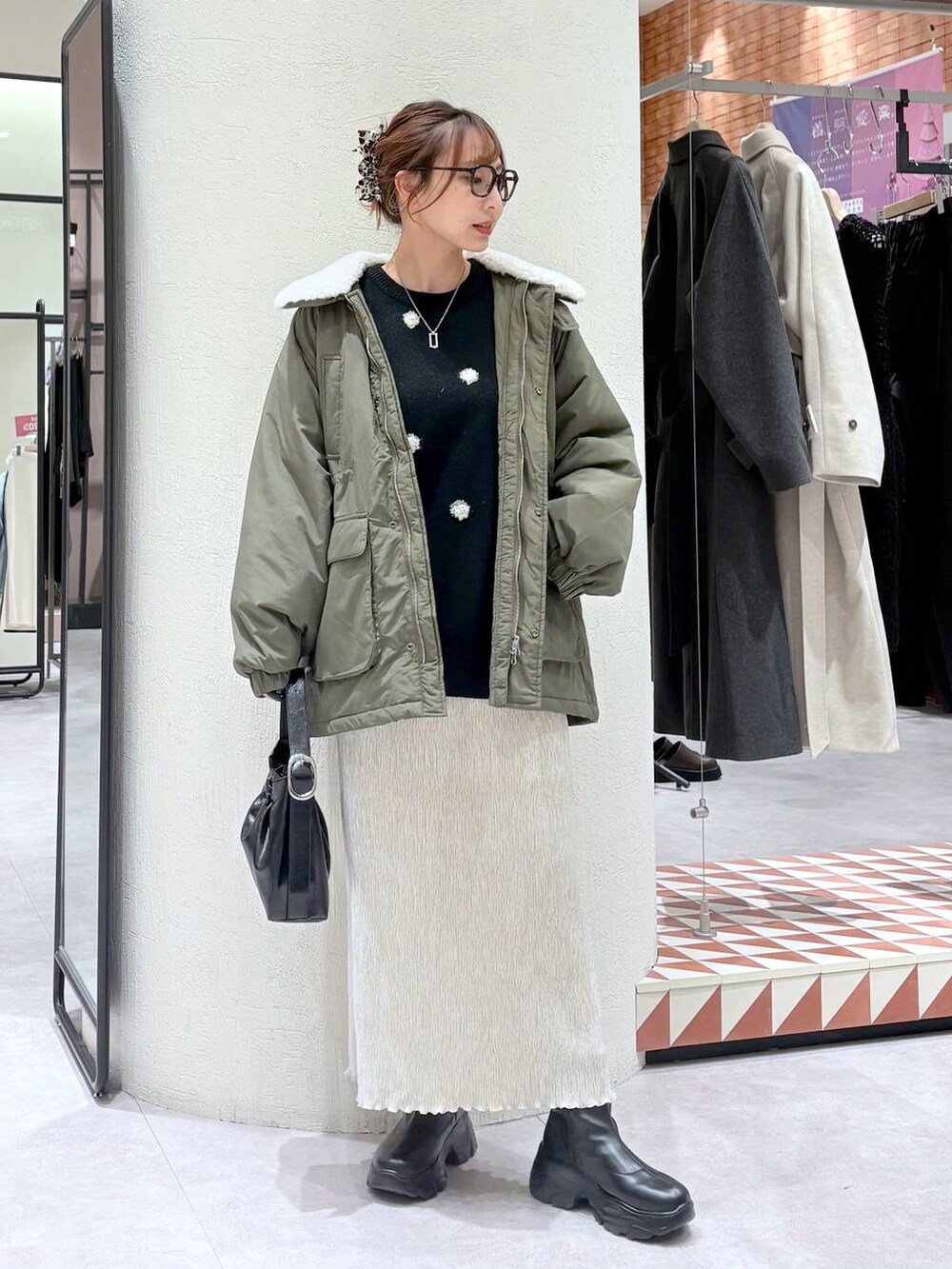 ブラック系のブーツ、グリーン系のその他アウター、ホワイト系のスカートを着用したレディースの冬コーディネートの5枚目の写真