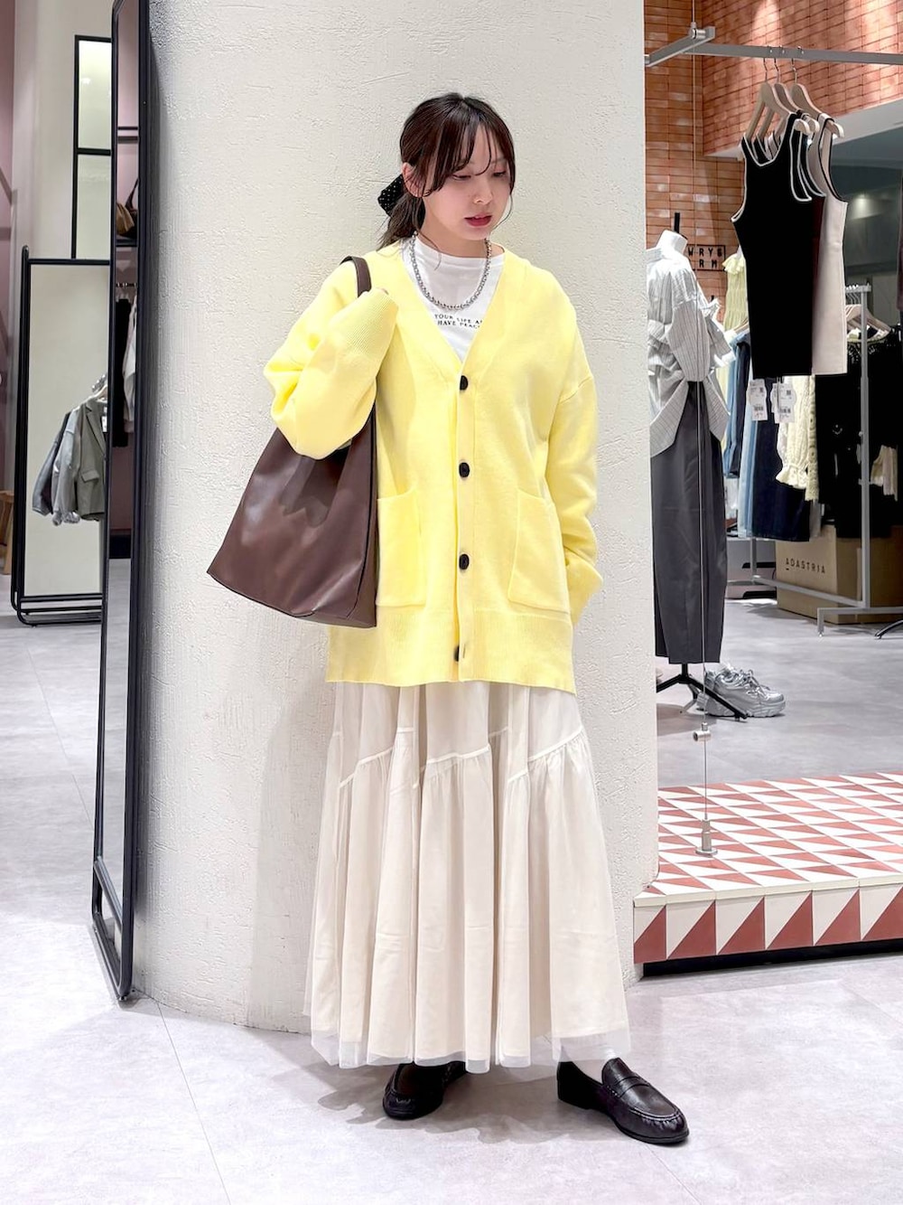 ブラウン系のショルダーバッグ、ブラウン系のローファー、ホワイト系のスカートを着用したレディースの春コーディネートの4枚目の写真