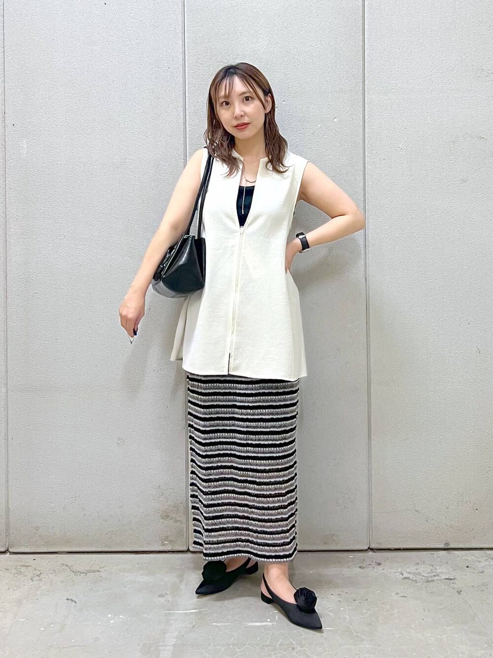 ブラック系のパンプス、ブラック系のTシャツ/カットソー、ブラック系のスカートを着用したレディースの秋コーディネートの4枚目の写真