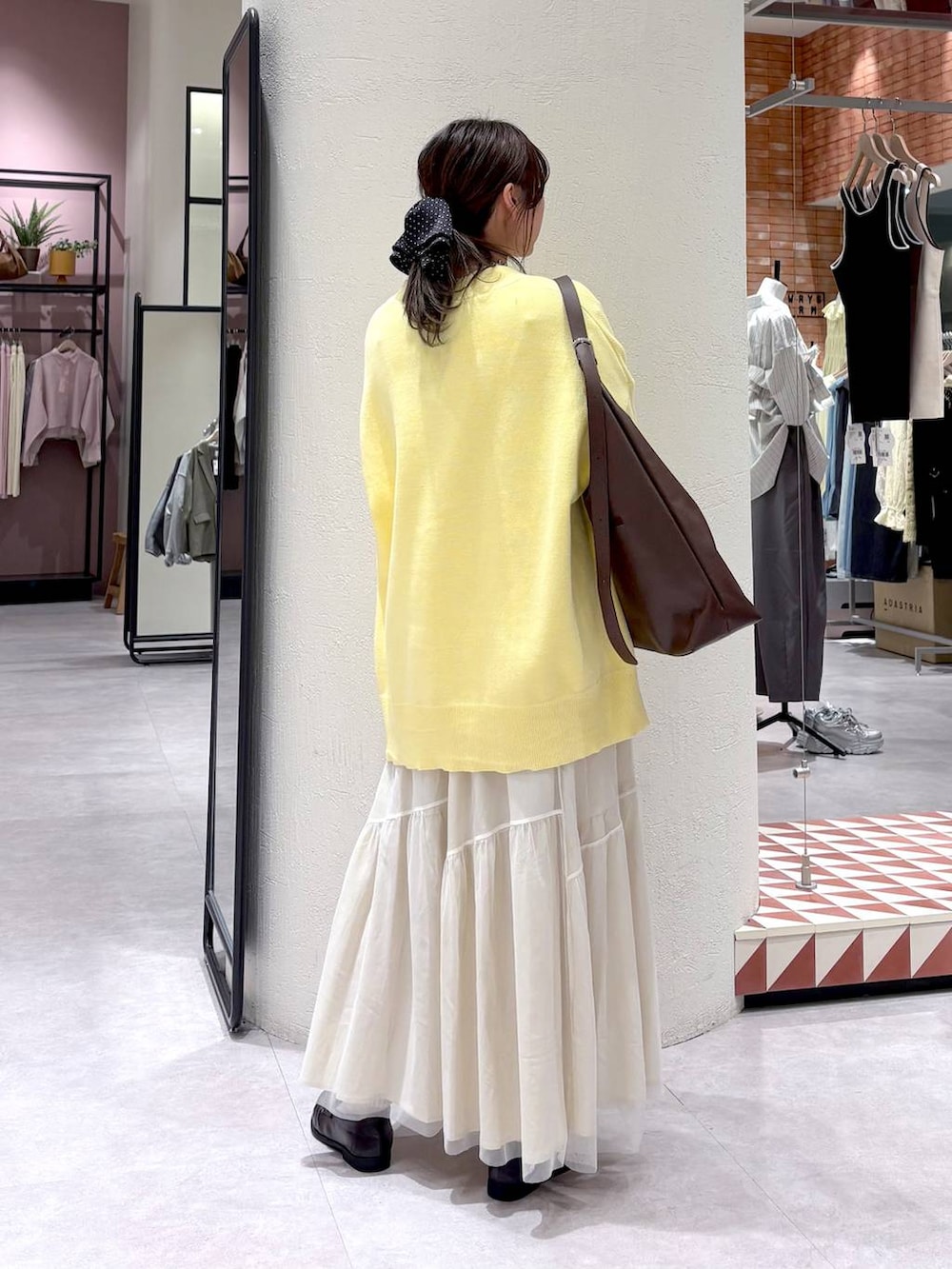 ブラウン系のショルダーバッグ、ブラウン系のローファー、ホワイト系のスカートを着用したレディースの春コーディネートの2枚目の写真