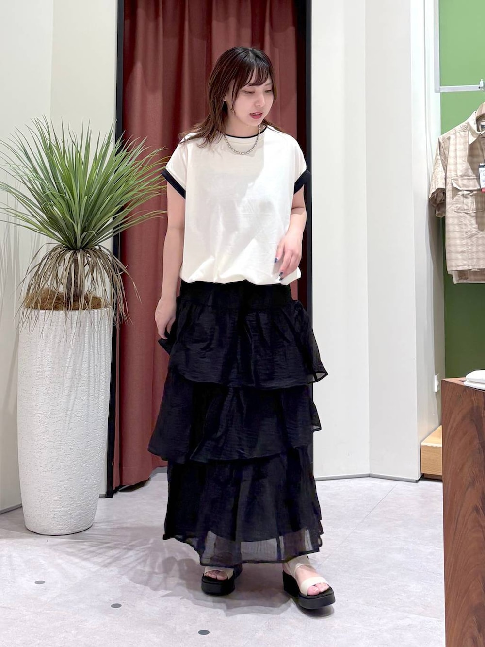 ホワイト系のTシャツ/カットソー、ホワイト系のサンダル、ブラック系のスカートを着用したレディースの夏コーディネートの2枚目の写真