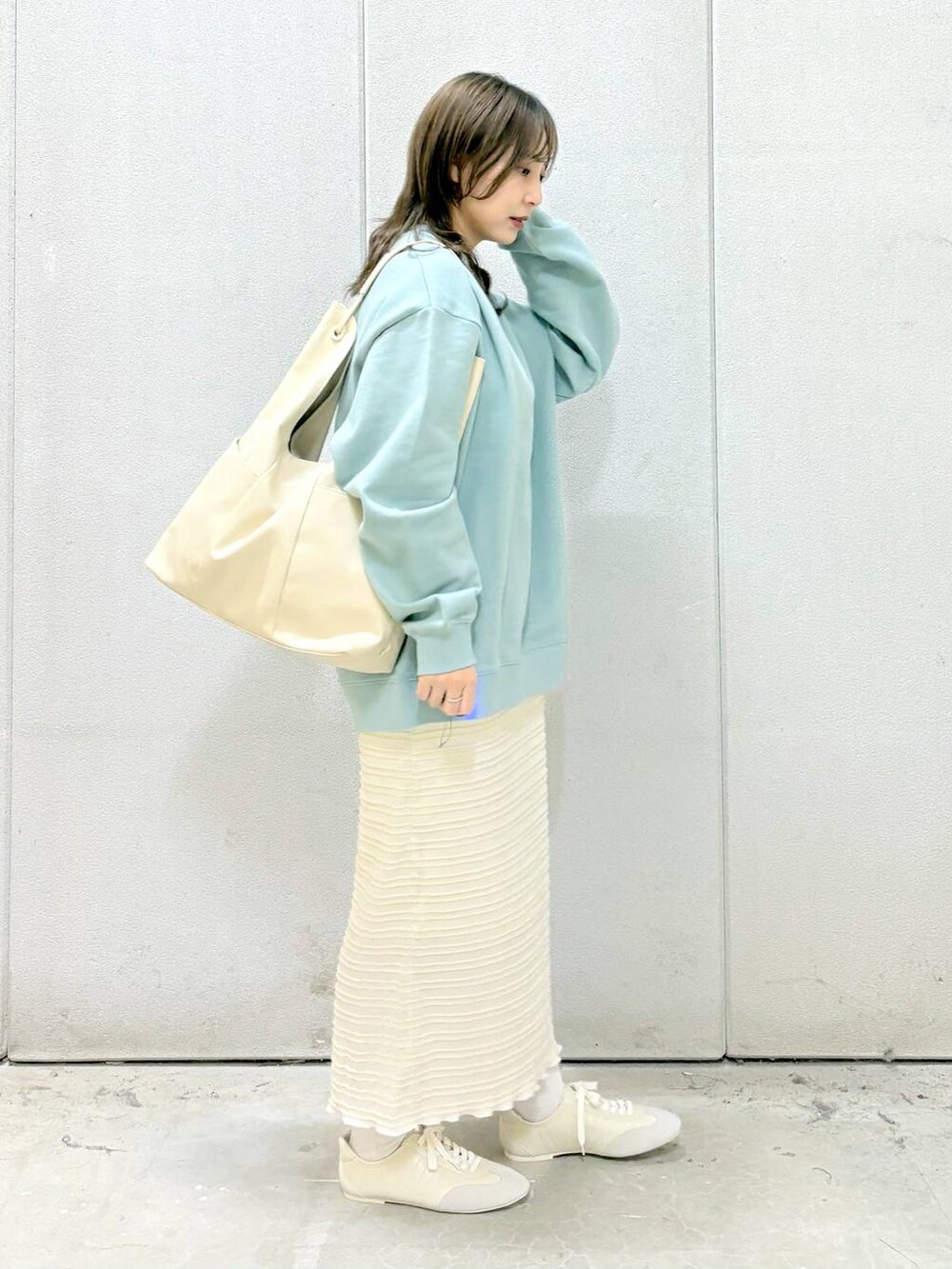 グリーン系のTシャツ/カットソー、ホワイト系のトートバッグ、ホワイト系のスニーカーを着用したレディースの冬コーディネートの5枚目の写真