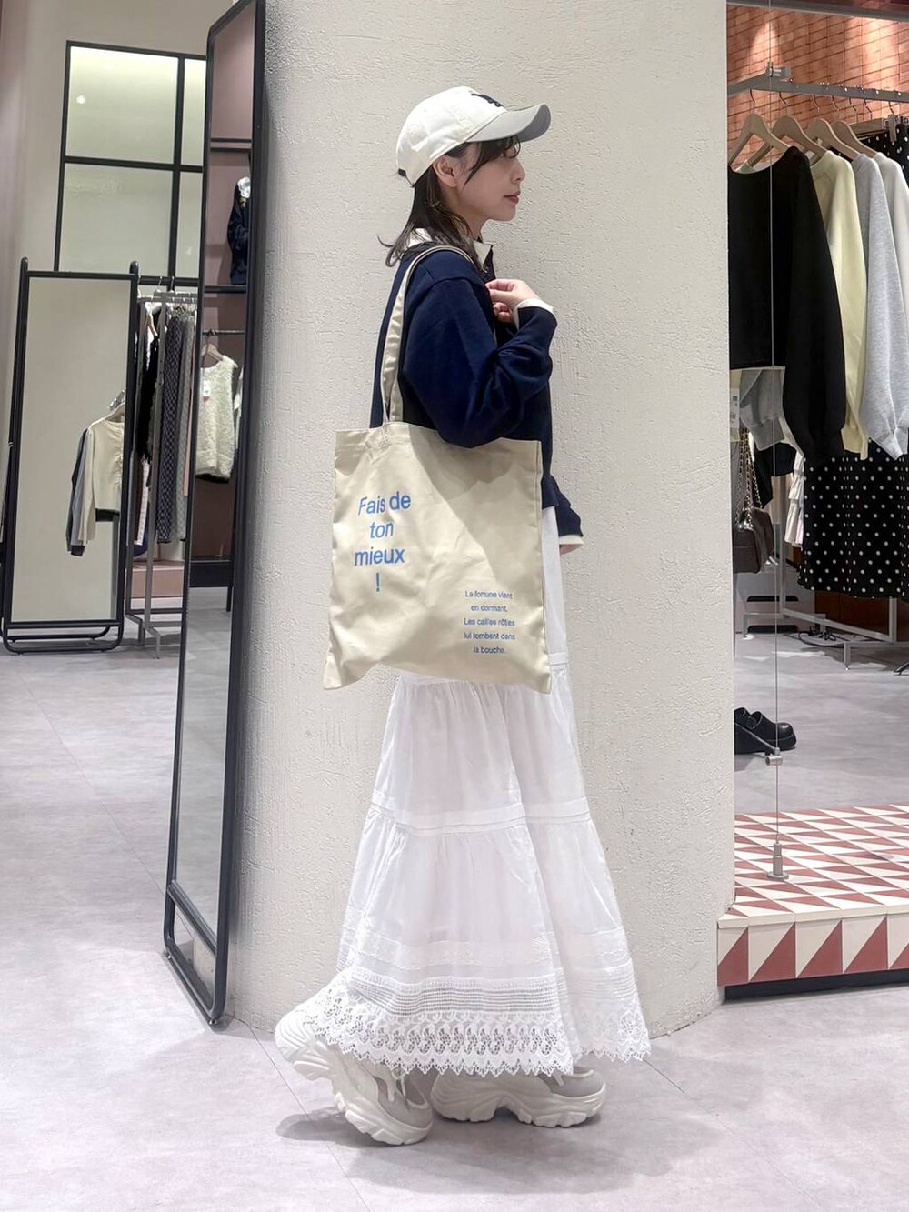 ベージュ系のトートバッグ、ホワイト系のスカート、ベージュ系のスニーカーを着用したレディースの冬コーディネートの3枚目の写真