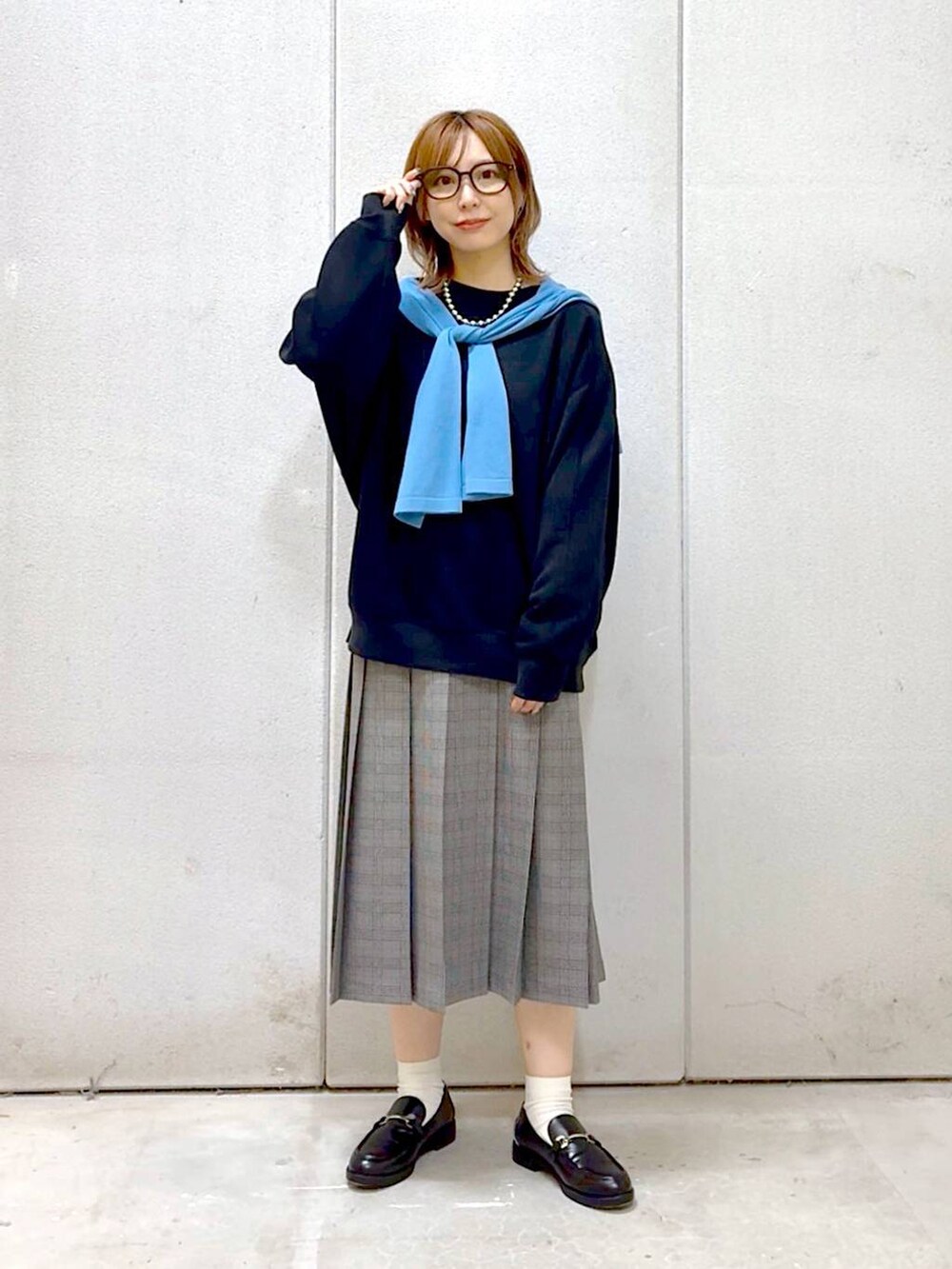 グレー系のスカート、ブラック系のスウェット、ブラック系のローファーを着用したレディースの秋コーディネートの7枚目の写真