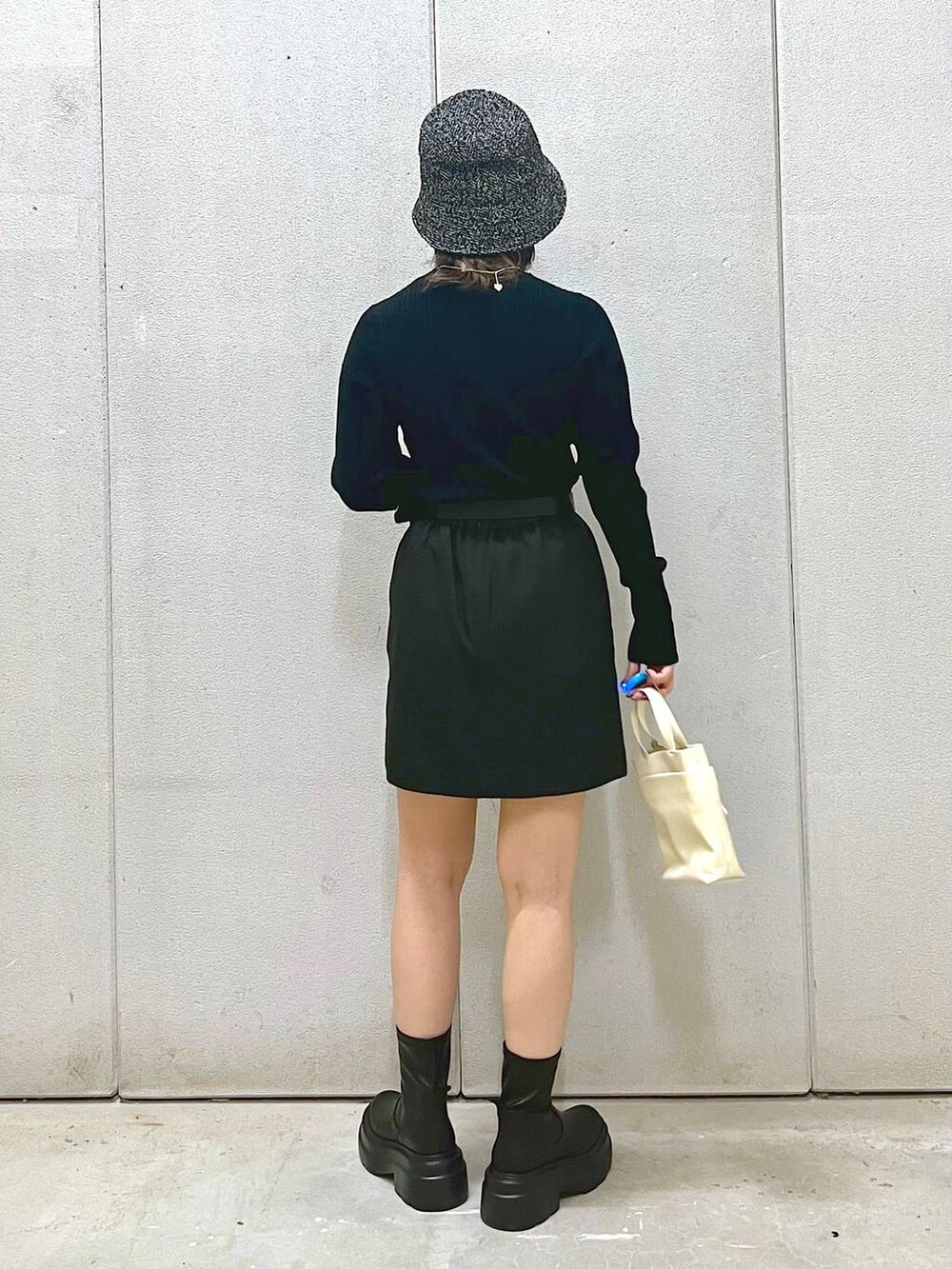 ホワイト系のその他アウター、ブラック系のニット/セーター、ブラック系のブーツを着用したレディースの秋コーディネートの3枚目の写真