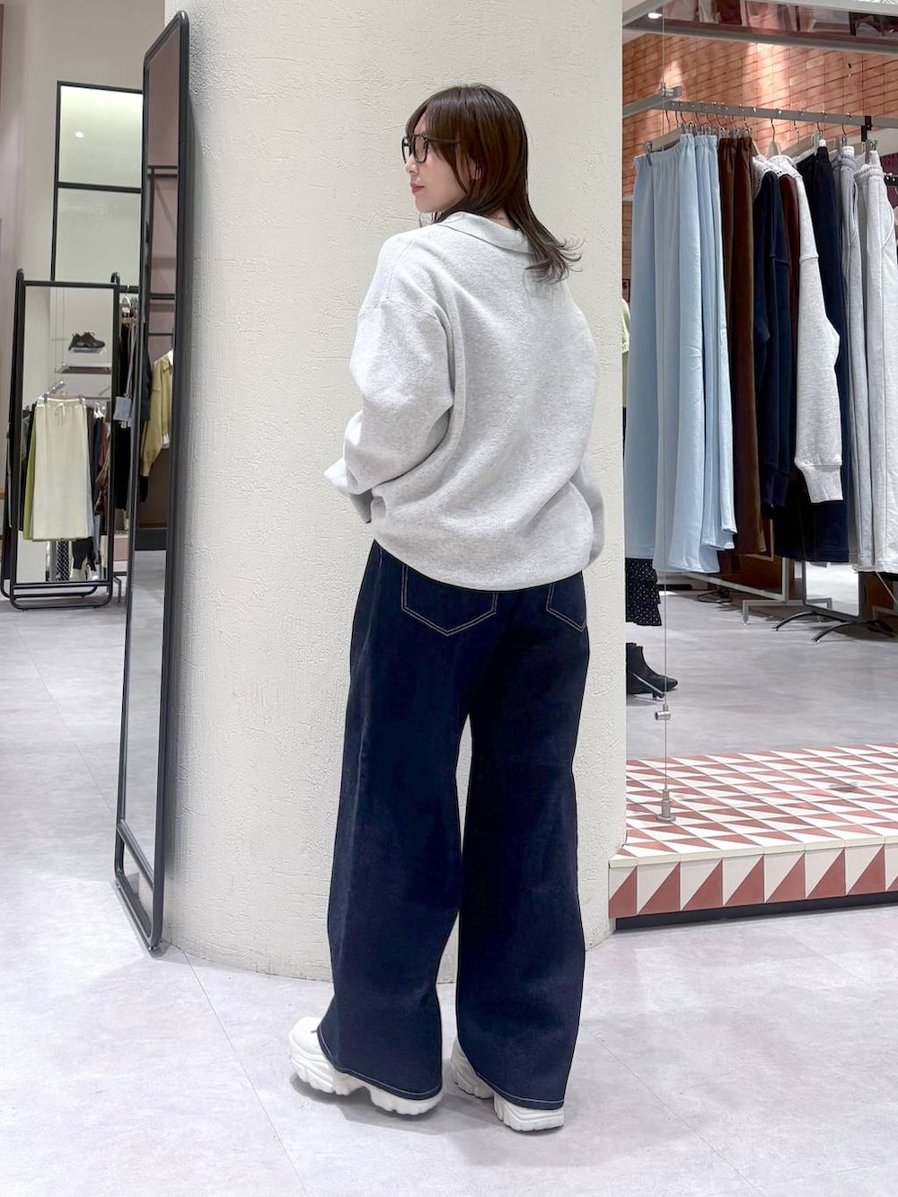 ブルー系のデニムパンツ、グレー系のニット/セーター、ホワイト系のスニーカーを着用したレディースの冬コーディネートの3枚目の写真