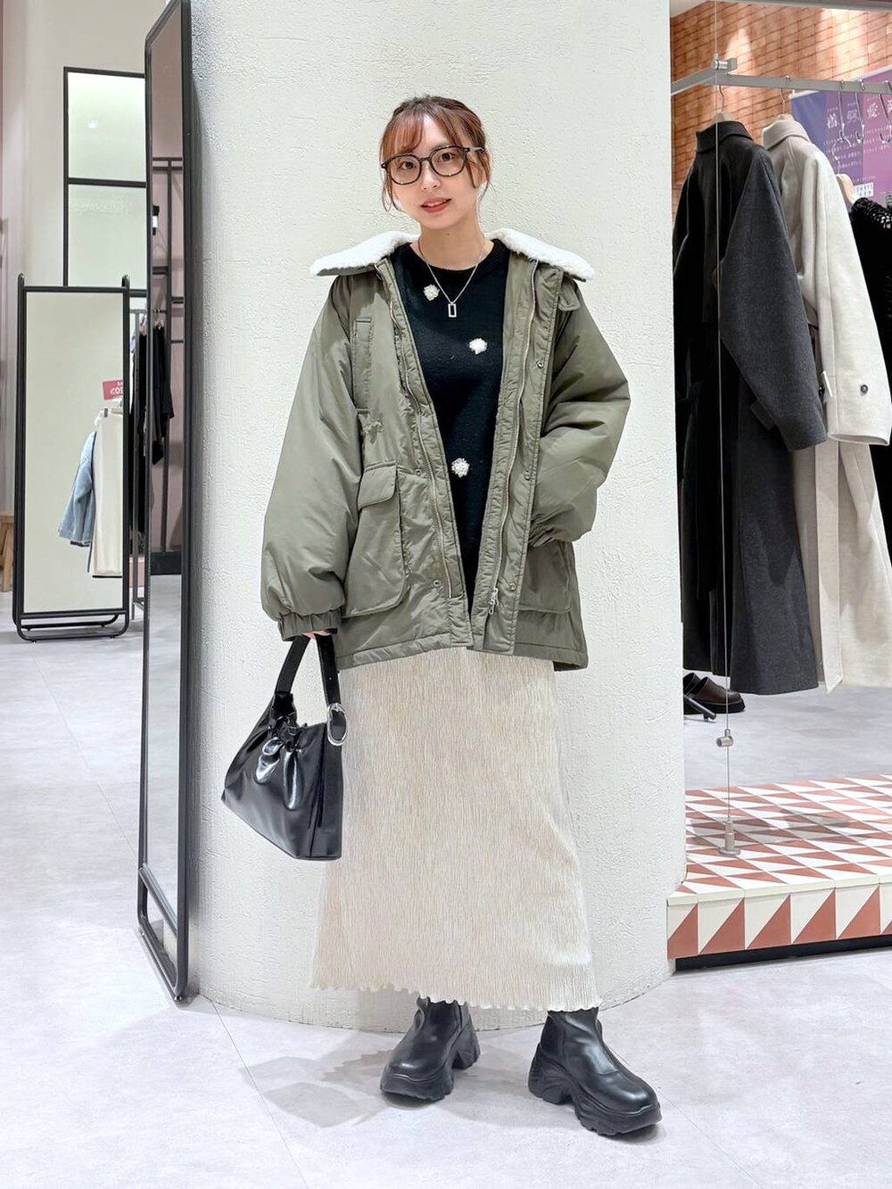 ブラック系のブーツ、グリーン系のその他アウター、ホワイト系のスカートを着用したレディースの冬コーディネートの2枚目の写真