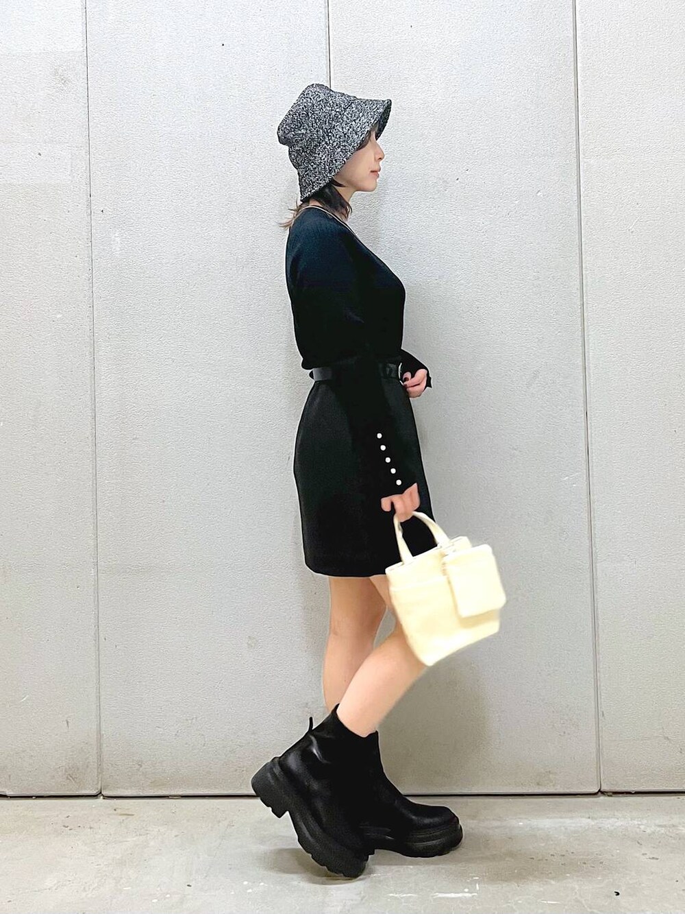 ホワイト系のその他アウター、ブラック系のニット/セーター、ブラック系のブーツを着用したレディースの秋コーディネートの4枚目の写真