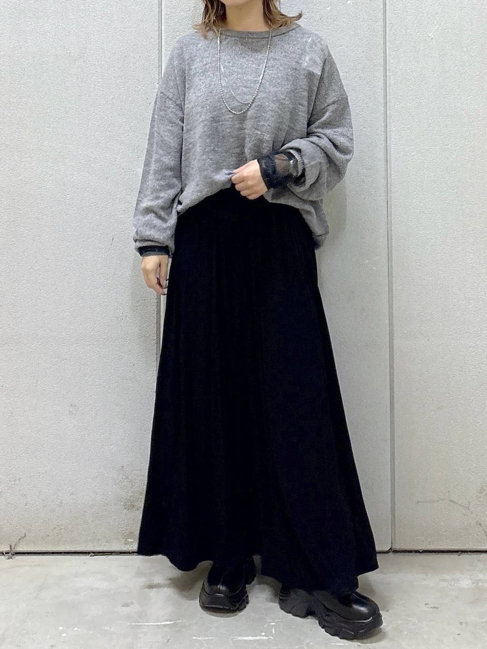 ブラック系のブーツ、ブラック系のスカート、グレー系のニット/セーターを着用したレディースの秋コーディネートの4枚目の写真