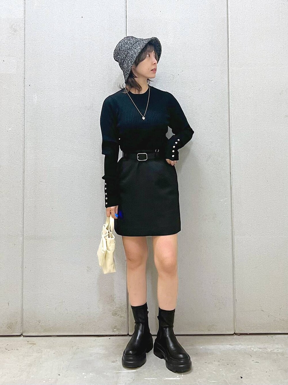 ホワイト系のその他アウター、ブラック系のニット/セーター、ブラック系のブーツを着用したレディースの秋コーディネートの2枚目の写真