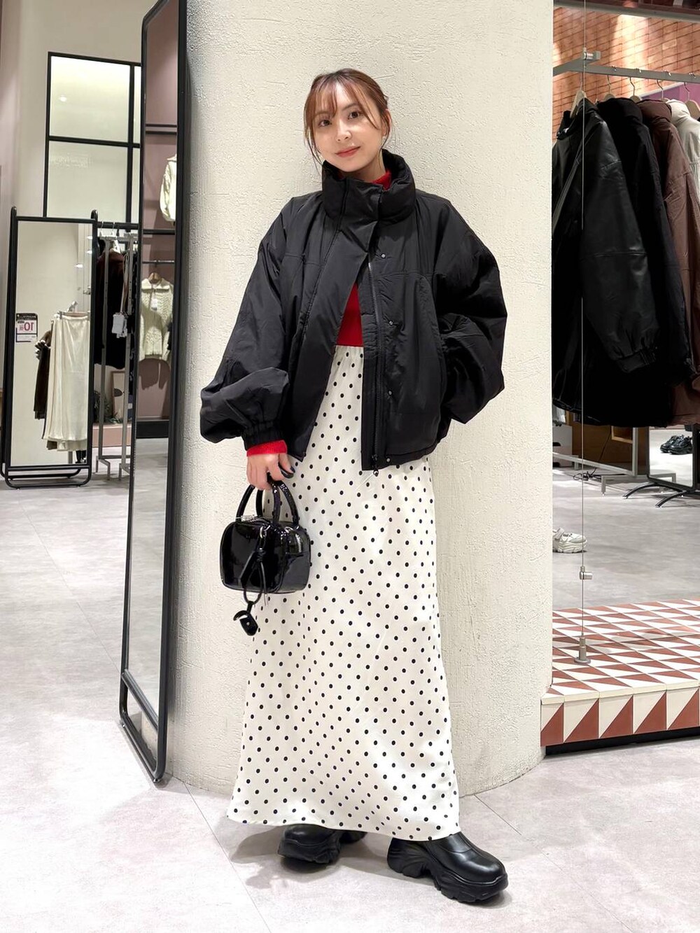 ブラック系のその他アウター、ブラック系のブーツ、ホワイト系のスカートを着用したレディースの秋コーディネートの5枚目の写真