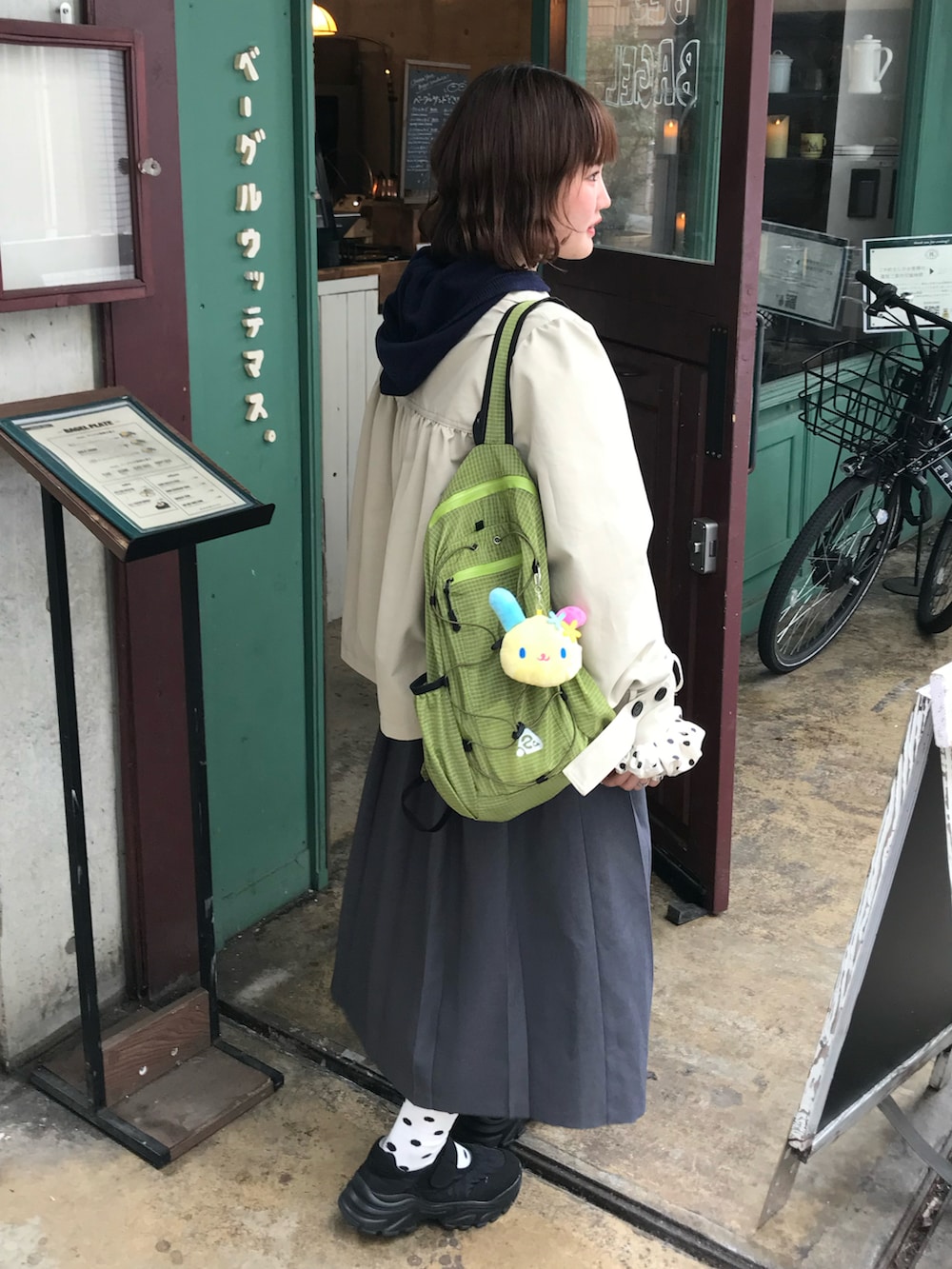 ブラック系のスニーカー、ベージュ系のその他アウター、グレー系のスカートを着用したレディースの春コーディネートの2枚目の写真