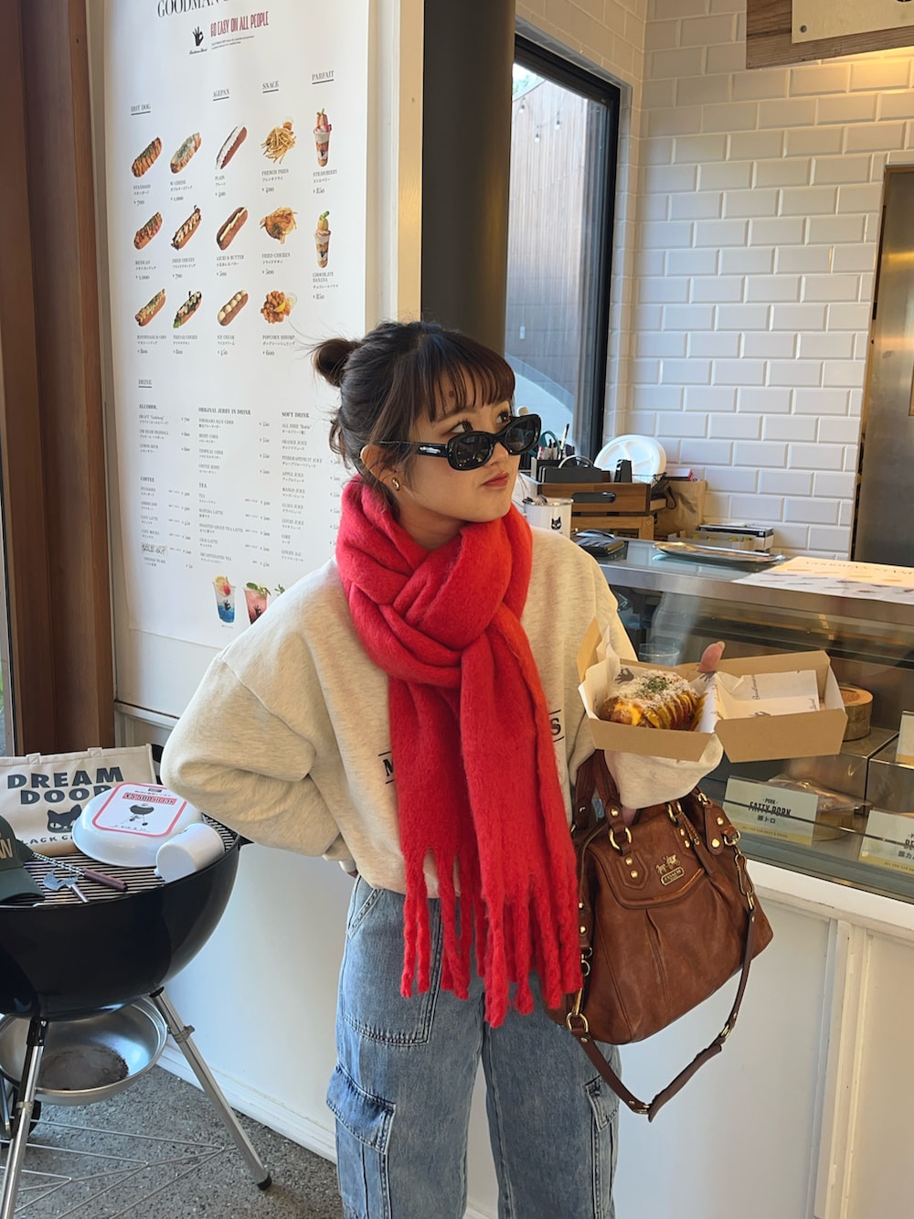 ブルー系のデニムパンツ、グレー系のスウェット、レッド系のマフラーを着用したレディースの冬コーディネートの2枚目の写真