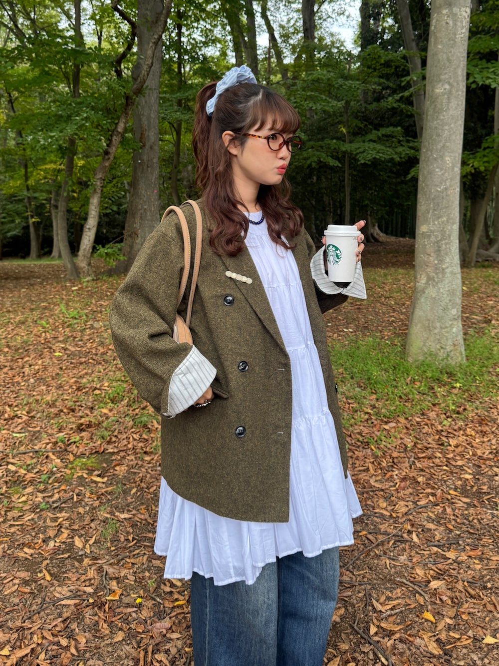 ベージュ系のボストンバッグ、ブルー系のデニムパンツ、ブラック系のブーツを着用したレディースの秋コーディネートの2枚目の写真