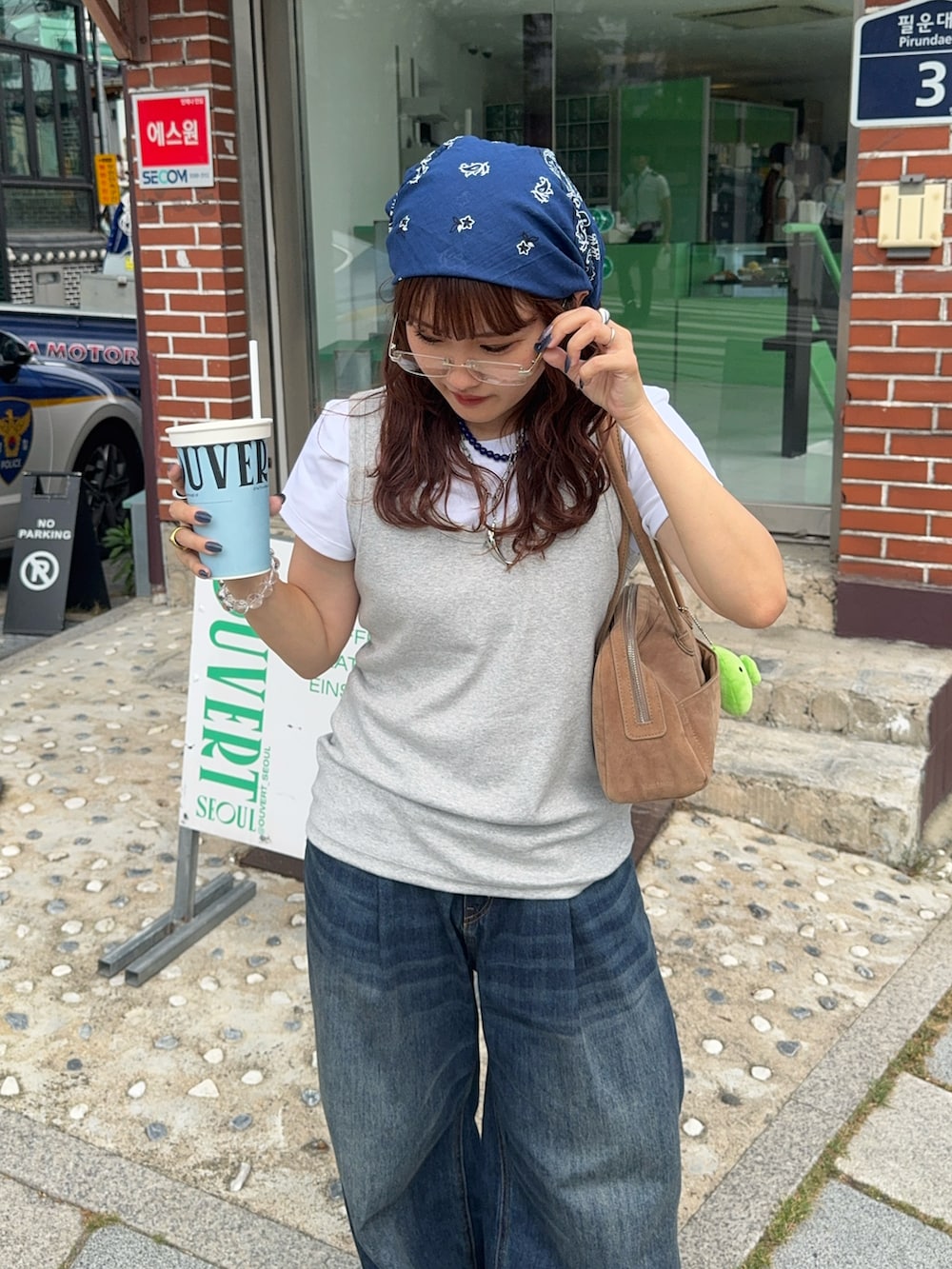 ブラック系のスニーカー、ブルー系のデニムパンツ、ベージュ系のボストンバッグを着用したレディースの夏コーディネートの2枚目の写真