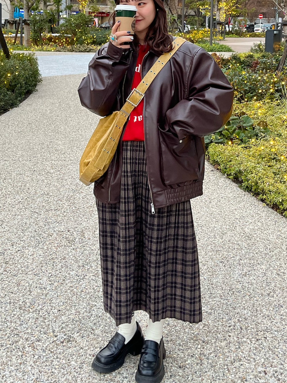 ブラウン系のライダースジャケット、イエロー系のショルダーバッグ、ブラウン系のスカートを着用したレディースの冬コーディネートの2枚目の写真